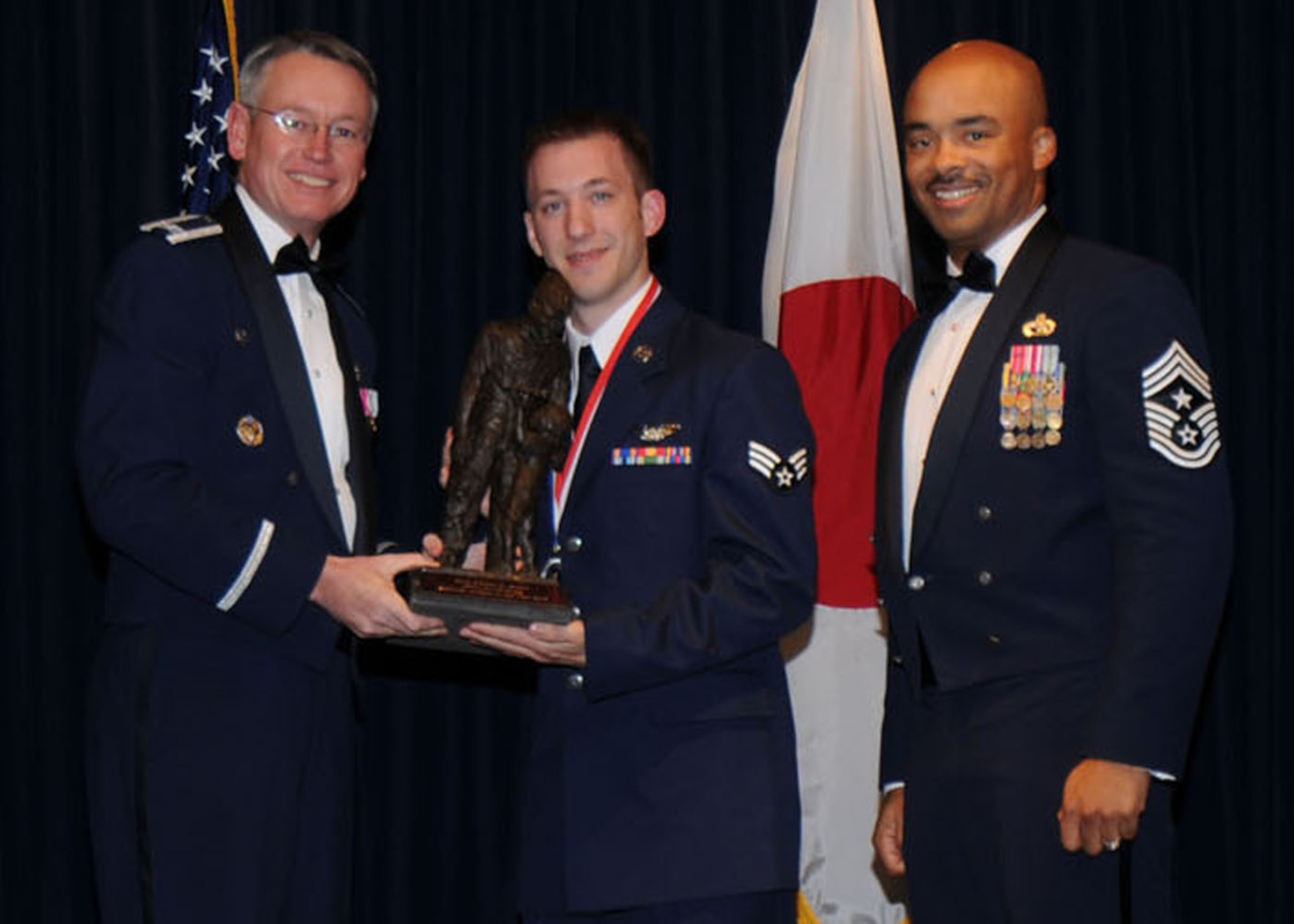 YOKOTA AIR BASE, Japan -- Colonel Jeff Newell, 374th Airlift Wing commander, and Chief Master Sgt. Linus Jordan, 374th AW command chief master sergeant, present Senior Airman Caleb J. Hefti, center, with the 374th AW Airman of the Year award Feb. 21. Airman Hefti is assigned to the 36th Airlift Squadron. (U.S. Air Force photo/Senior Airman Veronica Pierce)
