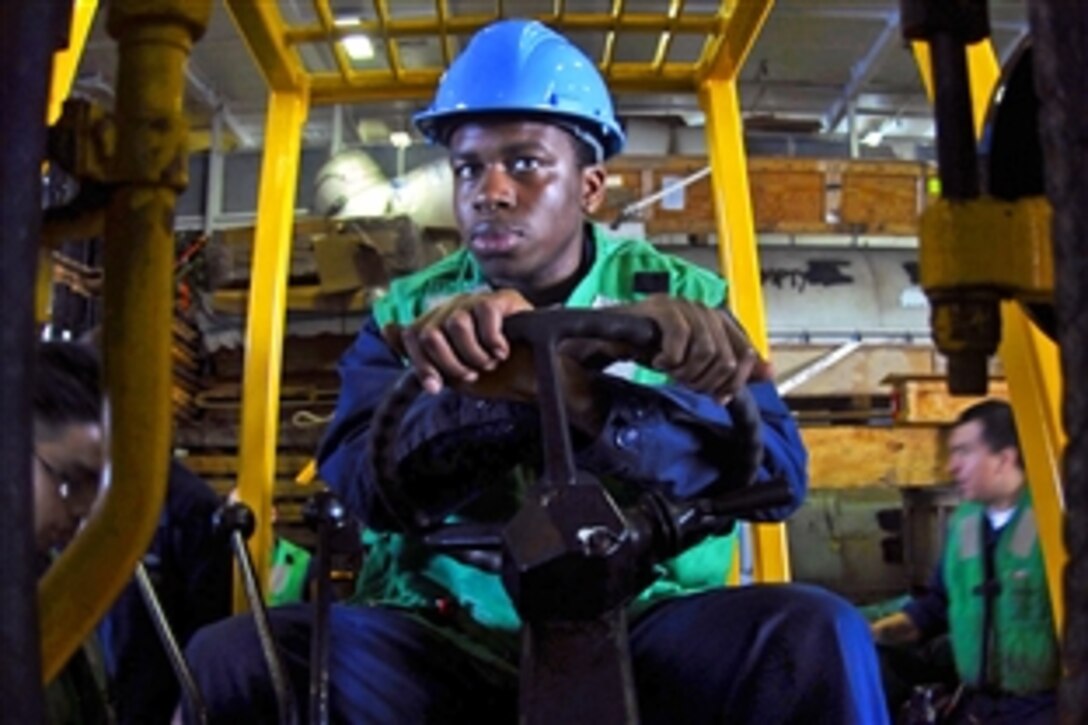 U.S. Navy Petty Officer 3rd Class Calvin Wright waits to move supplies with a forklift in the hangar bay aboard the aircraft carrier USS John C. Stennis during a replenishment at sea with the Military Sealift Command combat stores ship USNS San Jose  in the Pacific Ocean, Feb. 23, 2009.