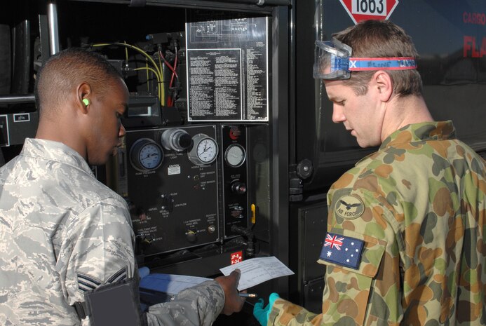 Senior Airman Ed McLean, left, a 99th Logistics Readiness Squadron fuels specialist, provides a fuel ticket to Royal Australian Air Force avionics technician Cpl. Daniel Johnson, after refueling his F-111 Aardvark jet during Red Flag 09-3 at Nellis Air Force Base, Nev., Feb. 24. Red Flag is a multi-national exercise providing a realistic environment to practice combat scenarios. The experience gained during the exercise is vital to the survival of air crews in combat. Cpl. Johnson is assigned to the 6th Squadron RAAF Base Amberley, Queensland, Australia. (U.S. Air Force Photo by Senior Airman Larry E. Reid Jr.)