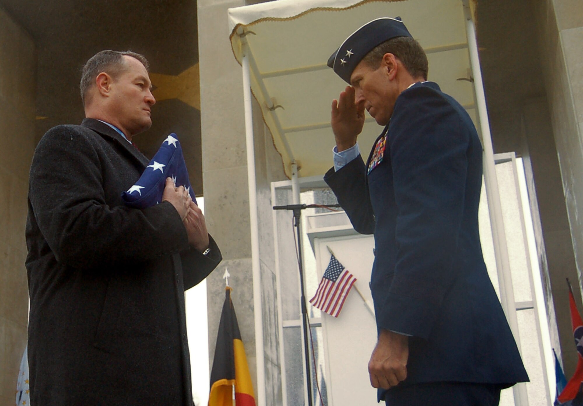 Maj. Gen. Thomas B. Wright salutes a folded flag held by U.S. Army retired Brig. Gen. Steven R. Hawkins to pay respects to the nine fallen Airmen of the McMurray Crew in the Army Air Corps who are no longer missing in action Feb. 20 at the Henri-Chapelle Cemetery and Memorial in Belgium. The B-24 bomber crew's remains were discovered after more than 60 years in a field southwest of Berlin. General Wright is the operations deputy chief of staff of operations for Supreme Headquarters Allied Powers Europe. General Hawkins is the director of the European region for the American Battle Monuments Commission. (U.S. Air Force photo/2nd Lt. Kathleen Polesnak) 
