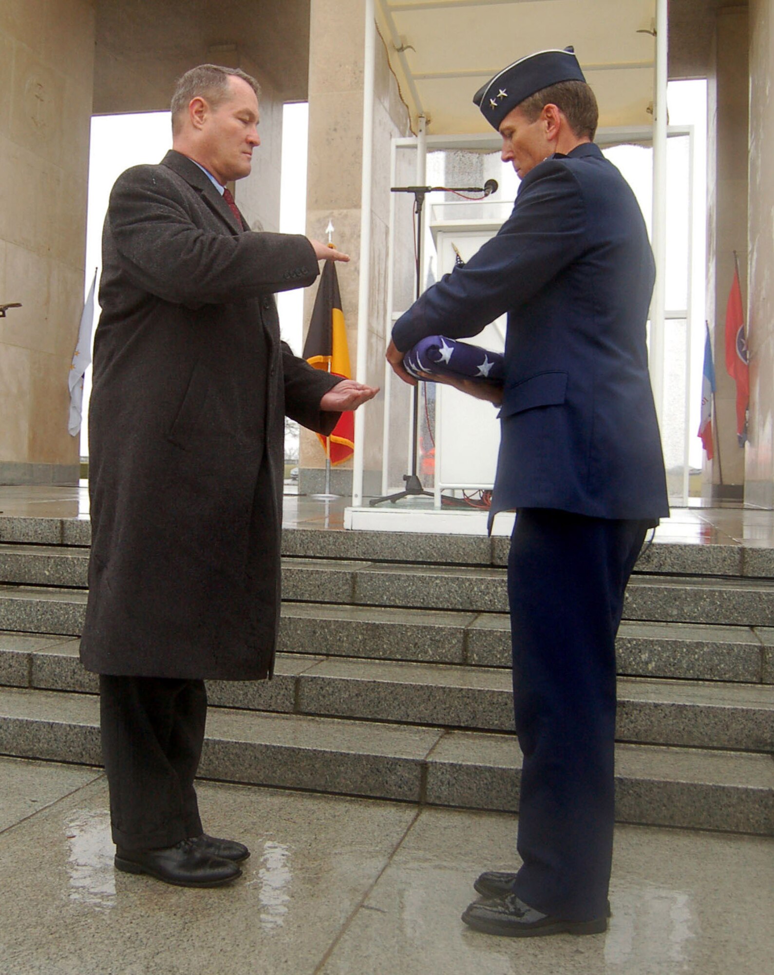 Maj. Gen. Thomas B. Wright hands a folded flag to U.S. Army retired Brig. Gen. Steven R. Hawkins to pay respects to the nine fallen Airmen of the McMurray Crew in the Army Air Corps who are no longer missing in action Feb. 20 at the Henri-Chapelle Cemetery and Memorial in Belgium. The B-24 bomber crew's remains were discovered after more than 60 years in a field southwest of Berlin. General Wright is the operations deputy chief of staff of operations for Supreme Headquarters Allied Powers Europe. General Hawkins is the director of the European region for the American Battle Monuments Commission. (U.S. Air Force photo/2nd Lt. Kathleen Polesnak) 
