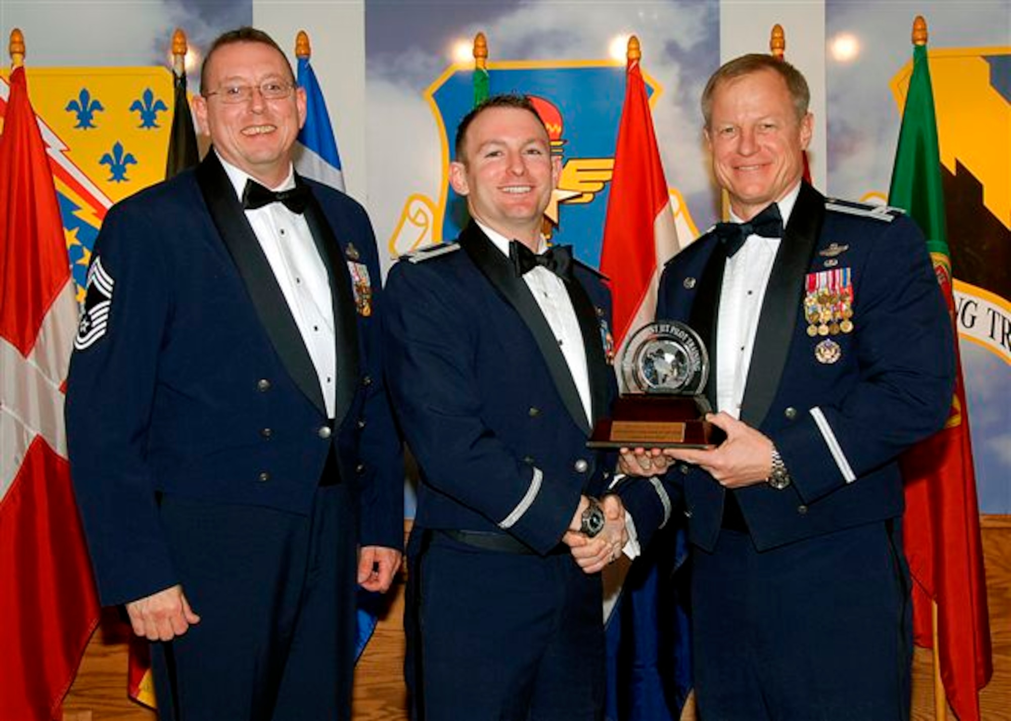 Capt. Brian Wood, center, accepts the award as the 80th Flying Training Wing's 2008 Senior Instructo Pilot of the Year. The 89th Flying Training Squadron captain was recognized for creating the Euro NATO Joint Jet Pilot Training T-6 pilot instructor training program from scratch. He implemented and executed two different training syllabi with 100 percent evaluation pass rate. Also pictured is Col. David Petersen, 80th FTW commander, and Chief Master Sgt. Norman Thierolf, the wing's command chief. (U.S. Air Force photo) 