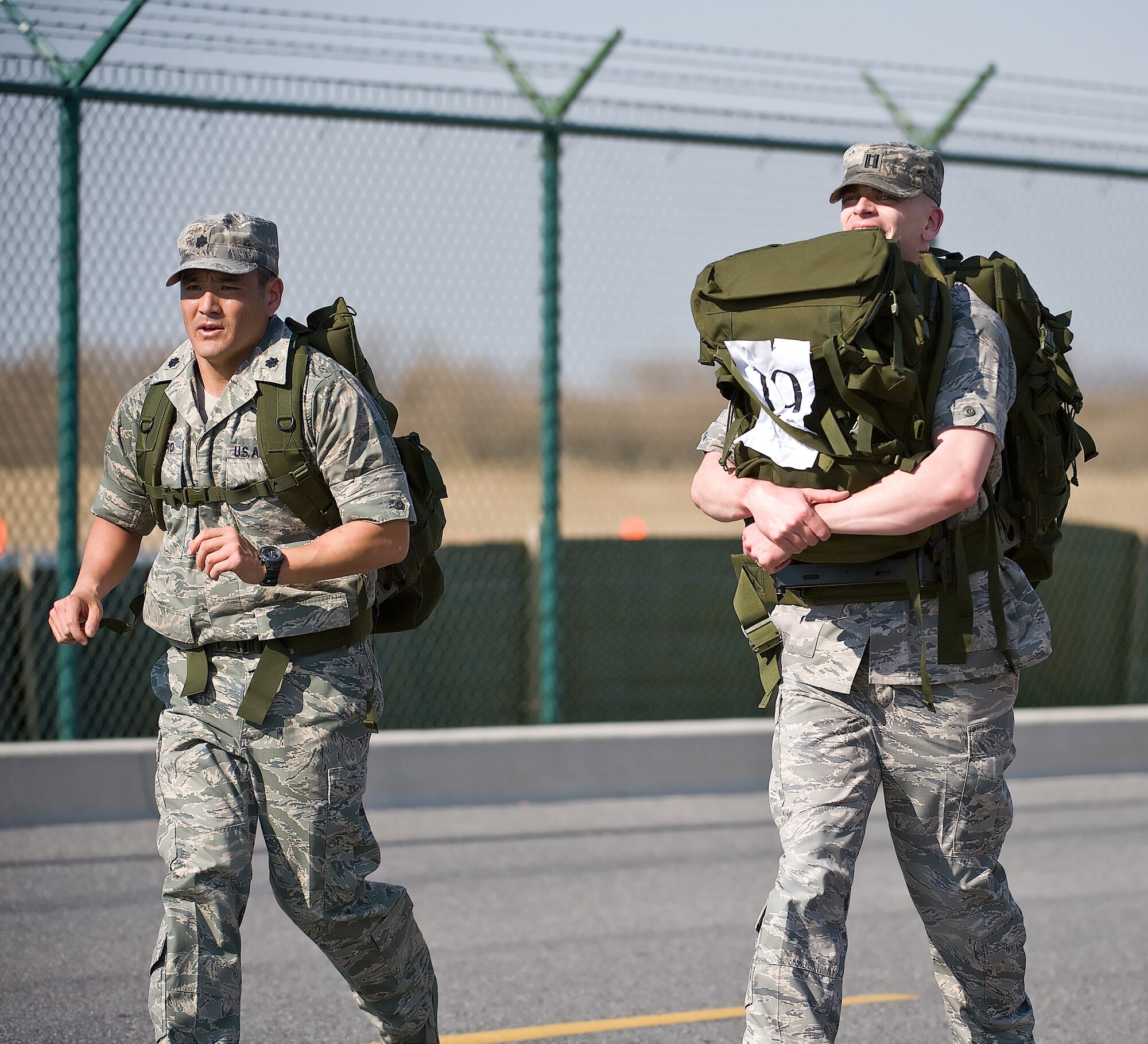 (Left to right) Lt. Col. David Kumashiro, 436th Operations Support Squadron commander, runs alongside Capt. Matt Born, 436th OSS, who carries his 30-pound rucksack and an additional 30-pound rucksack belonging to a teammate. Participants ran 10 kilometers with rucksacks during the 10th Annual Ruck March Feb. 21. (U.S. Air Force photo/ Roland Balik)