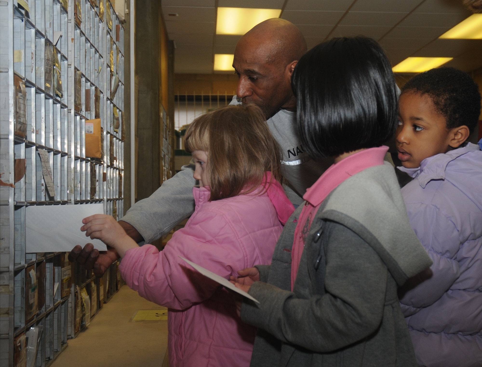 Derrick Foster, 48th Communications Squadron MOD postal worker, assists children from three Lakenheath Elementary School kindergarten classes file surprise letters to their parents at the RAF Lakenheath Post Office Feb. 20. While at the post office, the children learned how the postal service works here. (U.S. Air Force photo by Senior Airman Kristopher Levasseur)