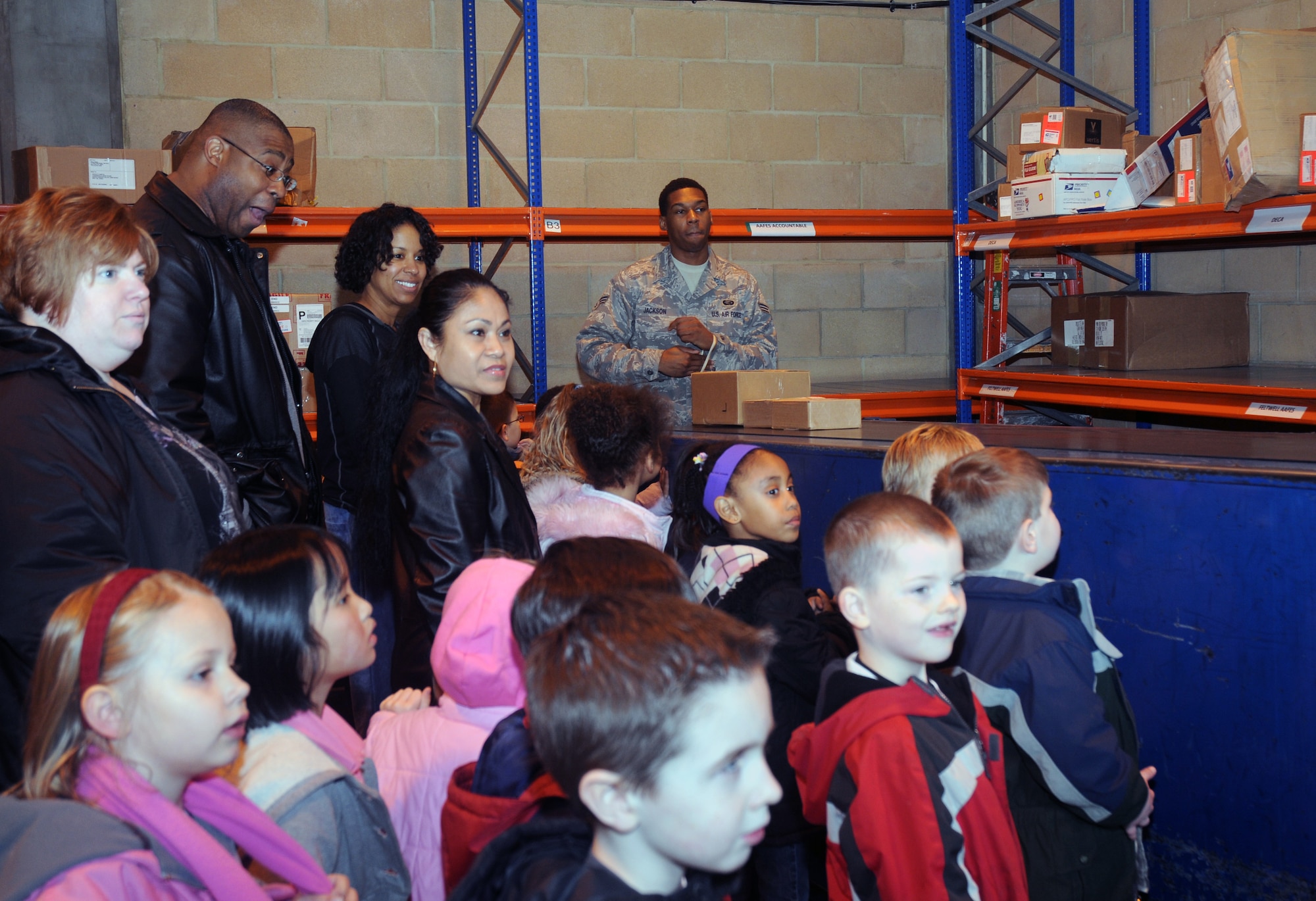 Senior Airman Sean Jackson, 48th Communications Squadron postal worker, demonstrates how to operate the package conveyer belt to children from three Lakenheath Elementary School kindergarten classes at the RAF Lakenheath Post Office Feb. 20. While at the post office, the children learned how the postal service works here. (U.S. Air Force photo by Senior Airman Kristopher Levasseur)