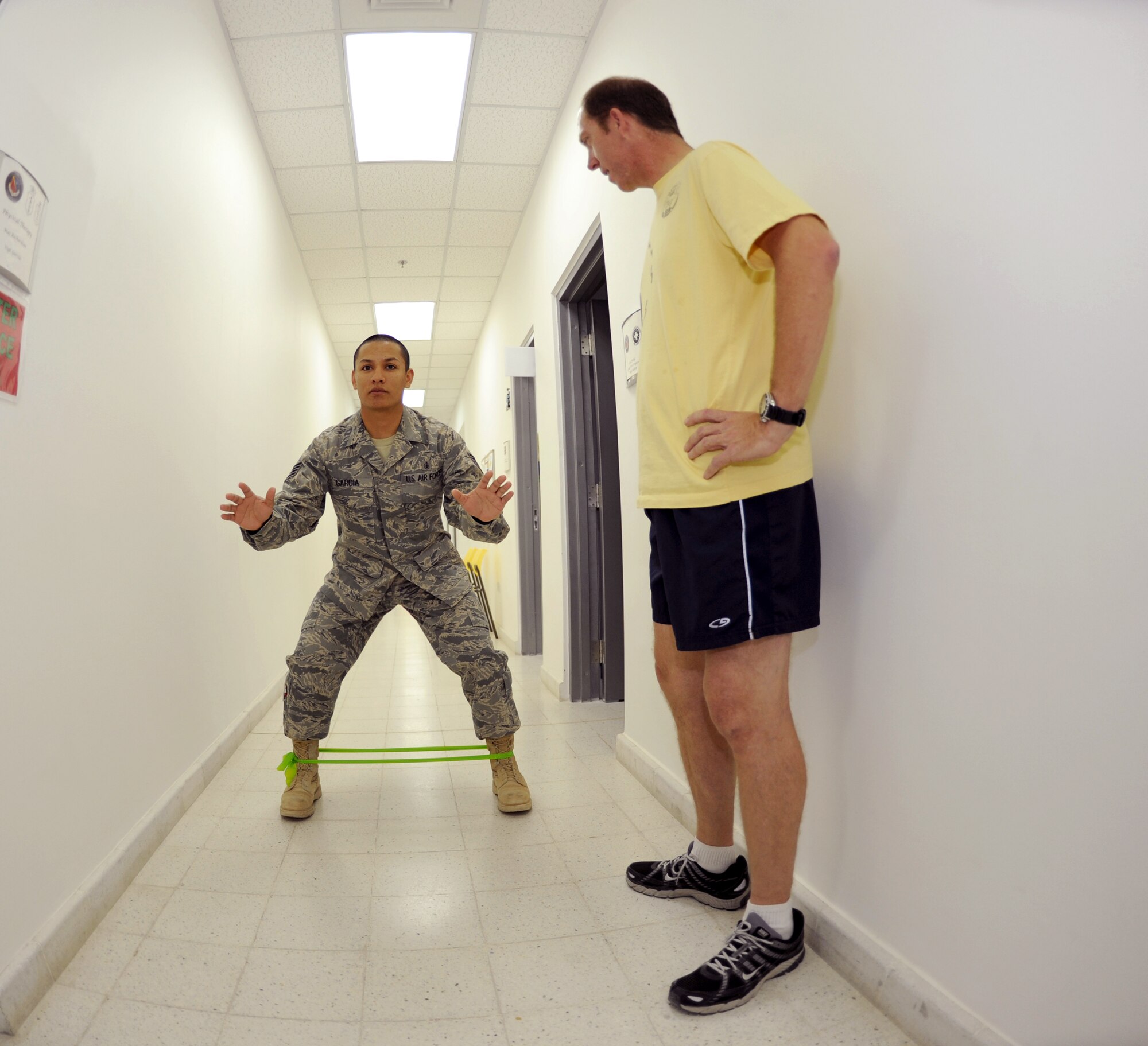 Staff Sergeant David Garcia, 379th Expeditionary Medical Group Noncommissioned Officer in Charge of Physical Therapy, demonstrates the forward squat walks with a resistant exercise band to Randy Fort, Retired Navy Petty Officer 1st Class, to help strengthen his legs from knee surgery, Feb. 24, 2009, at an undisclosed location in Southwest Asia.  Staff Sgt. Garcia hails from Fredericksburg, Texas and is deployed from Andrews Air Force Base, Md. and Mr. Fort hails from Riverview, Fla., both are here in support of Operations Iraqi and Enduring Freedom and Combined Joint Task Force - Horn of Africa.  (U.S. Air Force Photo by Airman 1st Class Andrew Satran/Released)