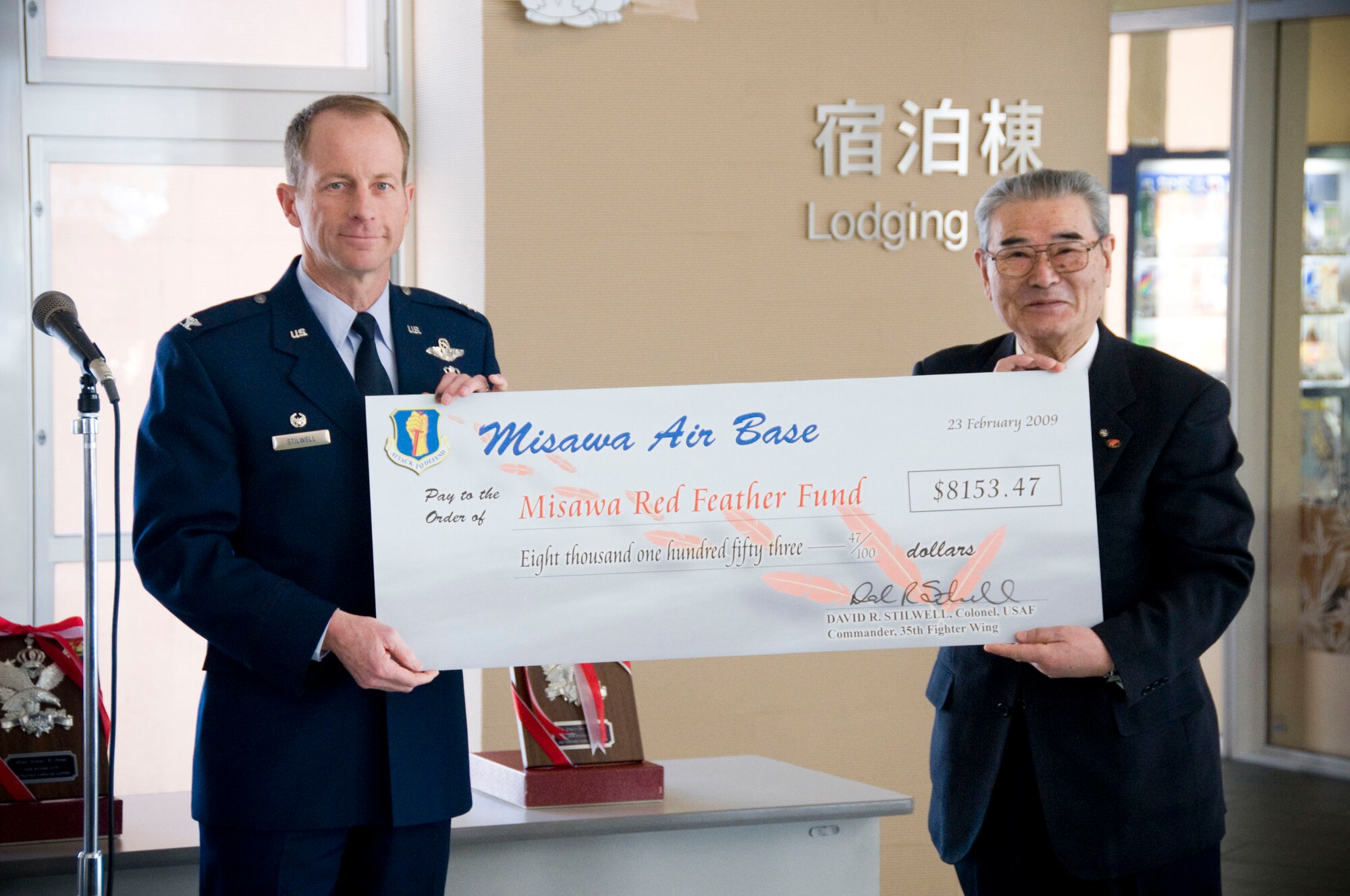 MISAWA CITY, Japan -- Col. David Stilwell, 35th Fighter Wing commander, presents Misawa Air Base's contribution to the annual Red Feather Campaign to Ishi Numata, Misawa Red Feather Community Chest Committee president, at the Misawa International Center Feb. 23, 2009. The Misawa Red Feather Committee is one of the 3,300 branches making up the Japanese Red Feather Community Chest, helping less-fortunate citizens throughout Japan. (U.S. Air Force photo by Staff Sgt. Samuel Morse)