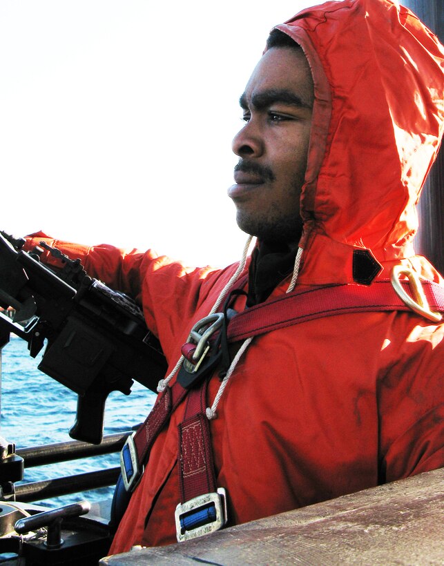 Navy Seaman DeAngelo Jackson Adams stands by a machine gun on the bridge of the USS Maryland, Feb. 17, 2009. 