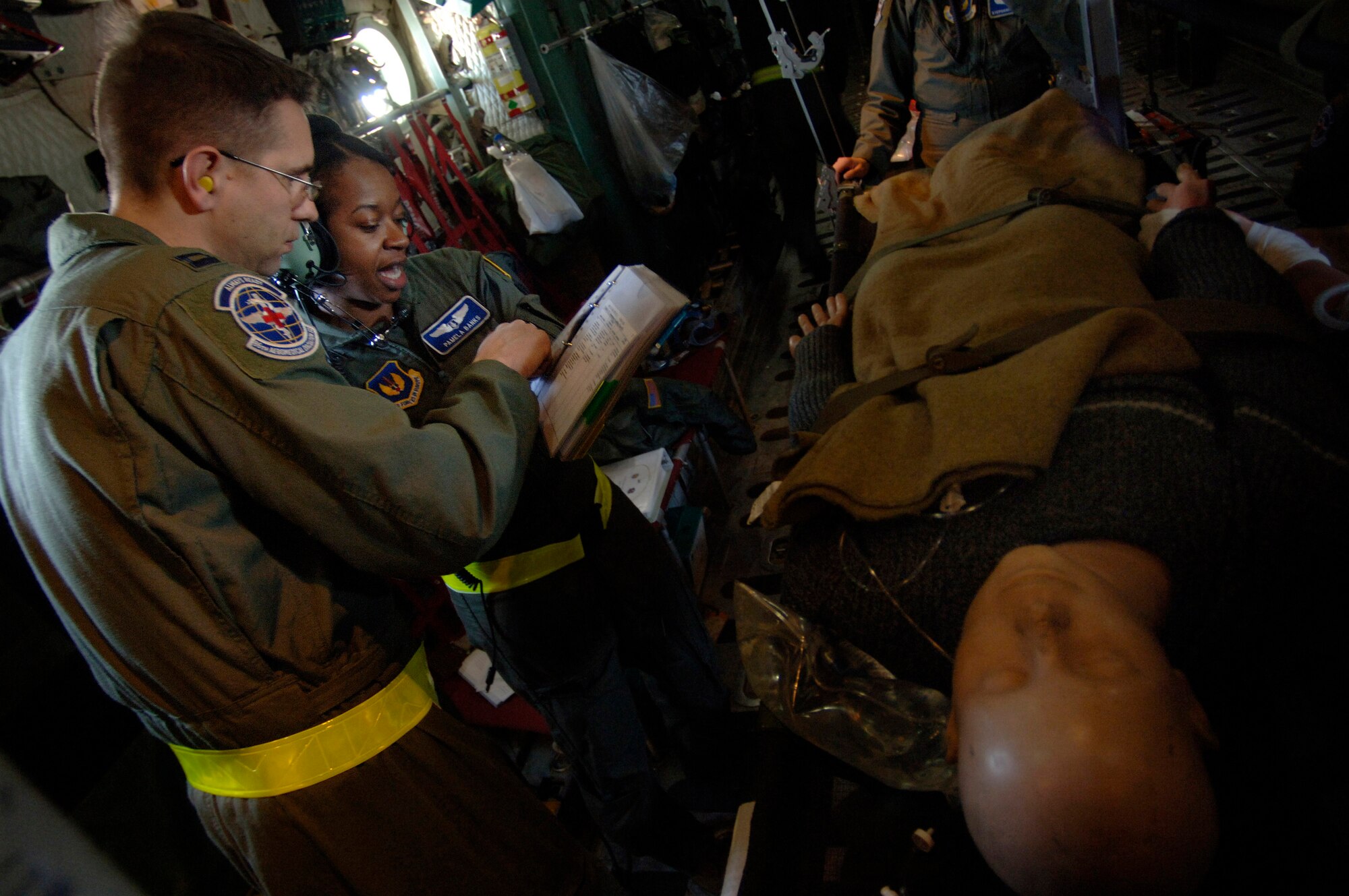 Capts. Troy Kinion and Pamela Banks cover a checklist detailing how to properly secure patients and medical equipment for a potentially rough landing in preparation for an emergency landing training scenario Feb. 19 aboard a C-130 Hercules flying over southern Germany. Captains Kinion and Banks are flight nurses. (Defense Department photo/Master Sgt. Scott Wagers) 
