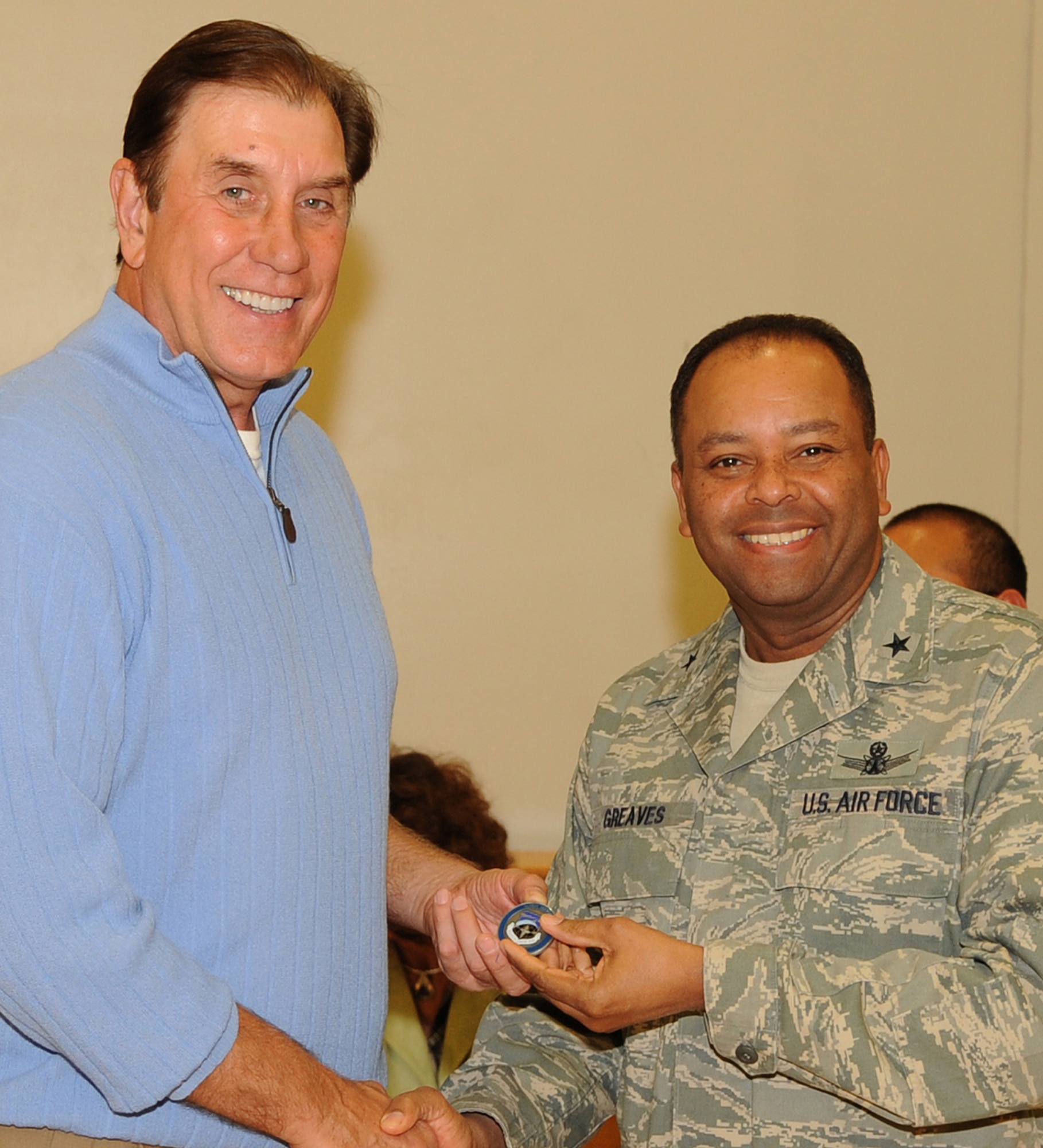 Brig. Gen. Samuel Greaves (right), MILSATCOM Wing commander, presents a unit coin to Rudy Tomjanovich, former NBA champion, gold medal head coach of the Houston Rockets and the Men’s Basketball team for the 2000 Olympics, and former head coach of the Los Angeles Lakers, Feb. 12.  Coach Tomjanovich visited the Space and Missile Center to support the troops as an invitation from his personal friend, Tom Meseroll, MILSATCOM Chief Engineer’s Office senior contractor. He stayed to watch team MCSW play its Intramural Basketball league game at the base gymnasium. (Photo by Stephen Schester) (released)

