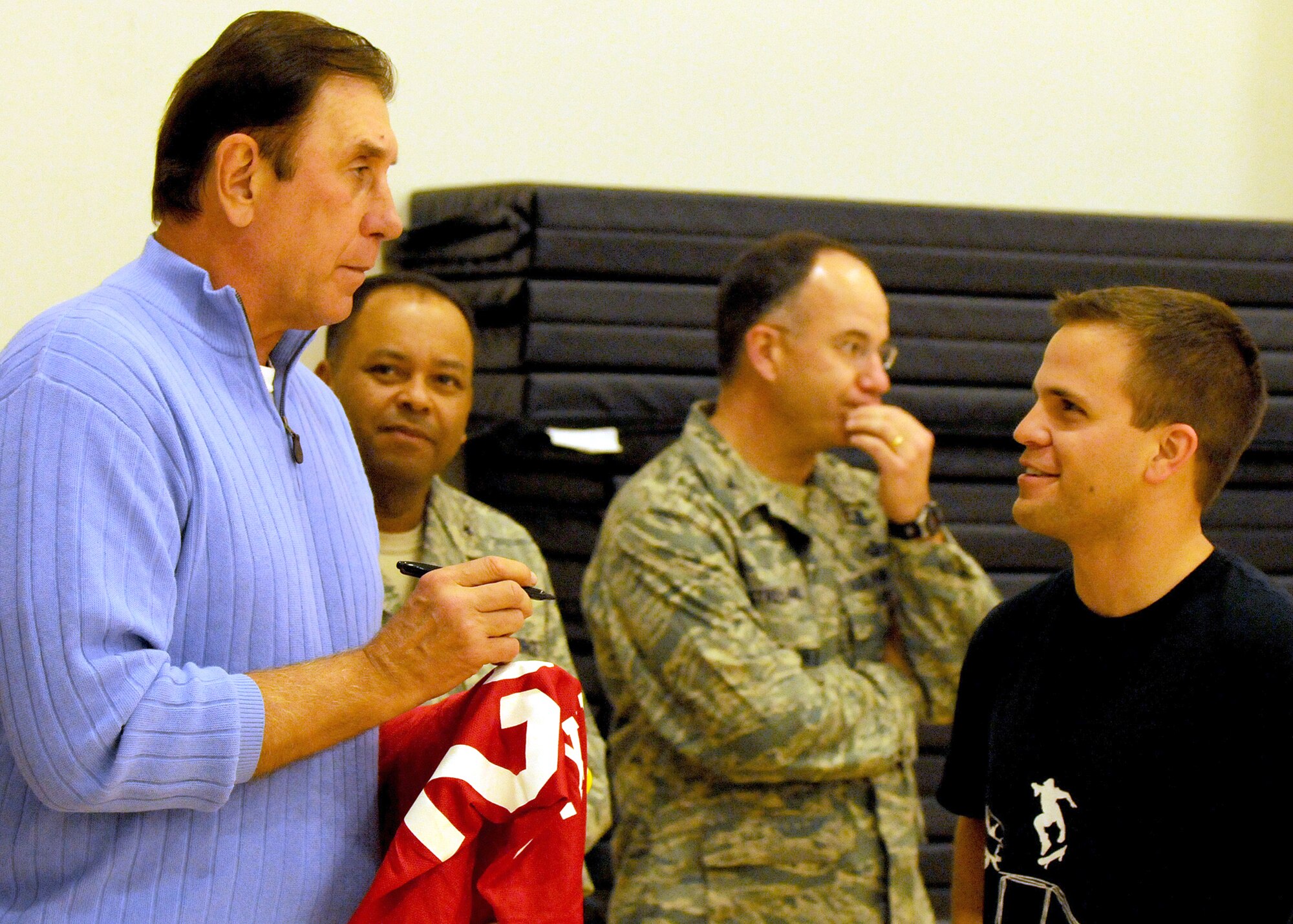 Rudy Tomjanovich (left), former NBA champion, gold medal head coach of the Houston Rockets and the Men’s Basketball team for the 2000 Olympics, and former head coach of the Los Angeles Lakers, autographs a Houston Rockets jersey for 1st Lt. Erik Torguson, Military Satellite Communications Systems Wing, before the intramural basketball game for the MILSATCOM Wing team, Feb. 12. Brig. Gen. Samuel Greaves (back, left), MILSATCOM Wing commander, and Col. Arnold Streland, MILSATCOM Wing TSAT Space Group commander, look on. Coach Tomjanovich visited the Space and Missile Center to support the troops as an invitation from his personal friend, Tom Meseroll, MILSATCOM Chief Engineer’s Office senior contractor. He stayed to watch team MCSW play its Intramural Basketball league game at the base gymnasium. (Photo by Stephen Schester) (released)