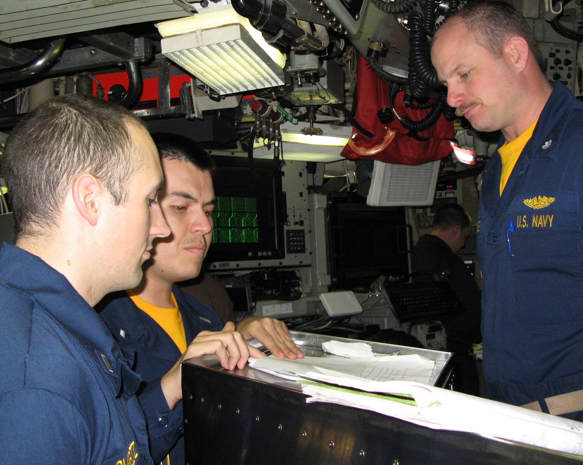 Navy Lt. j.g. Jeremy Smeltz (from left) and Lt. j.g. Juan Torres report to Cmdr. Jeffrey M. Grimes, the captain of the strategic missile submarine USS Maryland, during a battle drill Feb. 16. (Department of Defense photo/Gerry J. Gilmore)