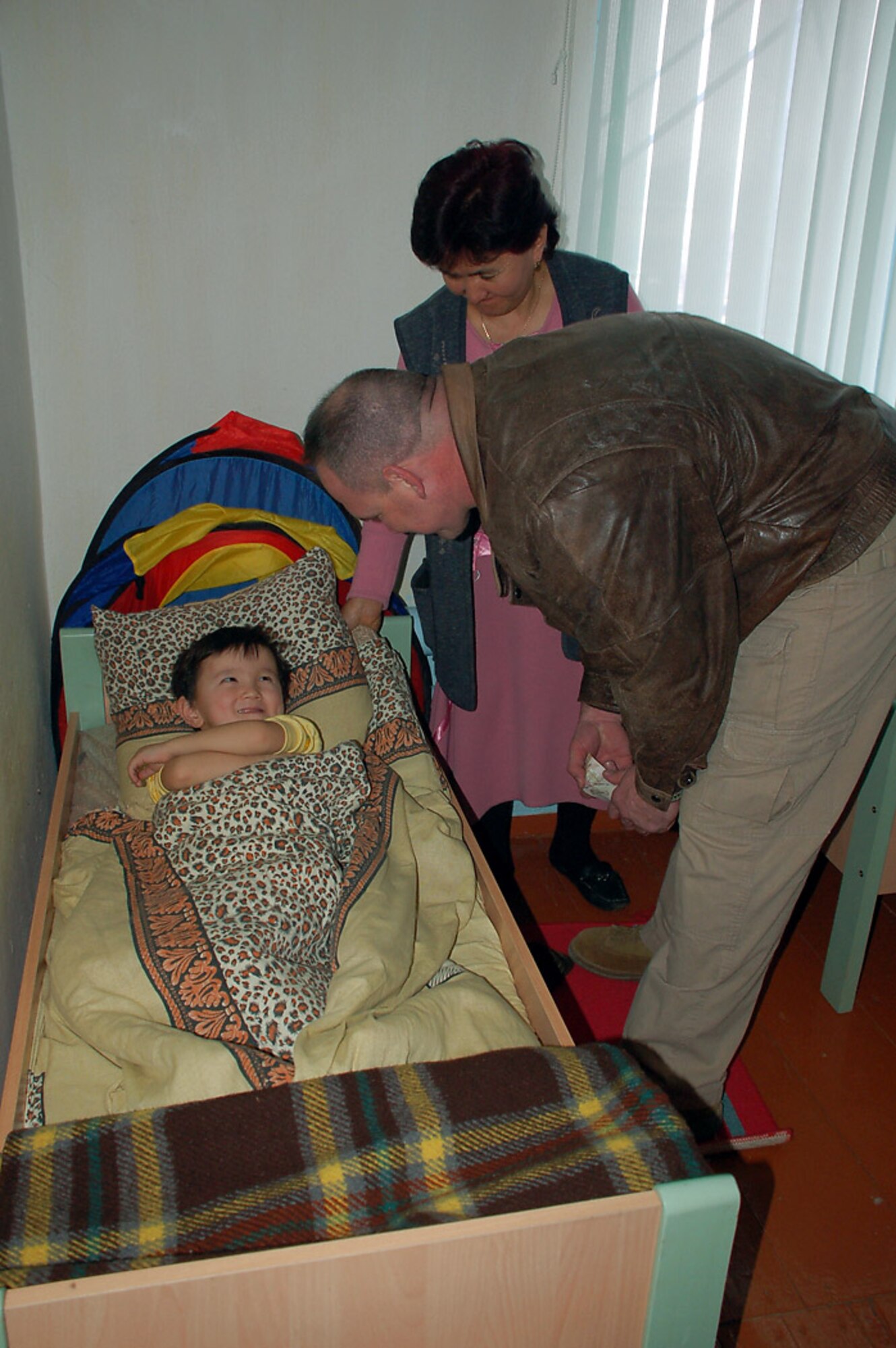 Manzura Kushbaeva looks on as Tech. Sgt. Chad West bids farewell to a child Feb. 20 at the Vasilievka Kindergarten School in Kyrgyzstan. Sergeant West is deployed with the 376th Expeditionary Security Forces Squadron at Manas Air Base, Kyrgyzstan, and is deployed from the Arkansas Air National Guard at Fort Smith. Ms. Kushbaeva is the principal of Vasilievka Kindergarten School. (U.S. Air Force photo/Tech. Sgt. Phyllis Hanson) 
