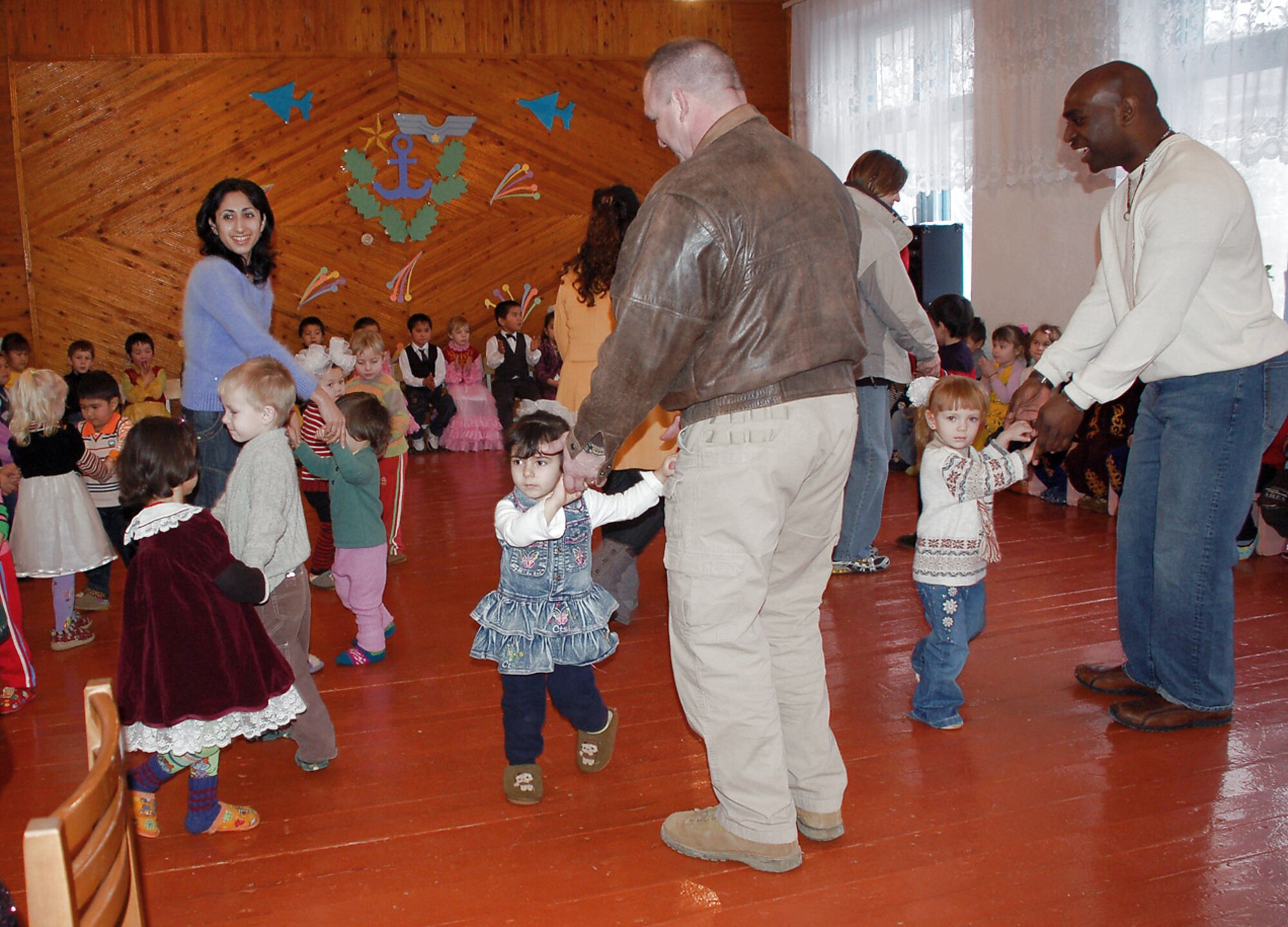 Kindergarteners at the Vasilievka Kindergarten School dance with Tech. Sgt. Chad West (left) and Staff Sgt. Chris Moore during a Feb. 20 visit by volunteers from nearby Manas Air Base, Kyrgyzstan. More than 75 children performed to thank the Manas AB volunteers for their support to help rebuild and improve their school over the past seven years. Sergeant West is assigned to the 376th Expeditionary Security Forces Squadron and Sergeant Moore is assigned to the 376th Air Expeditionary Wing staff. (U.S. Air Force photo/Tech. Sgt. Phyllis Hanson) 
