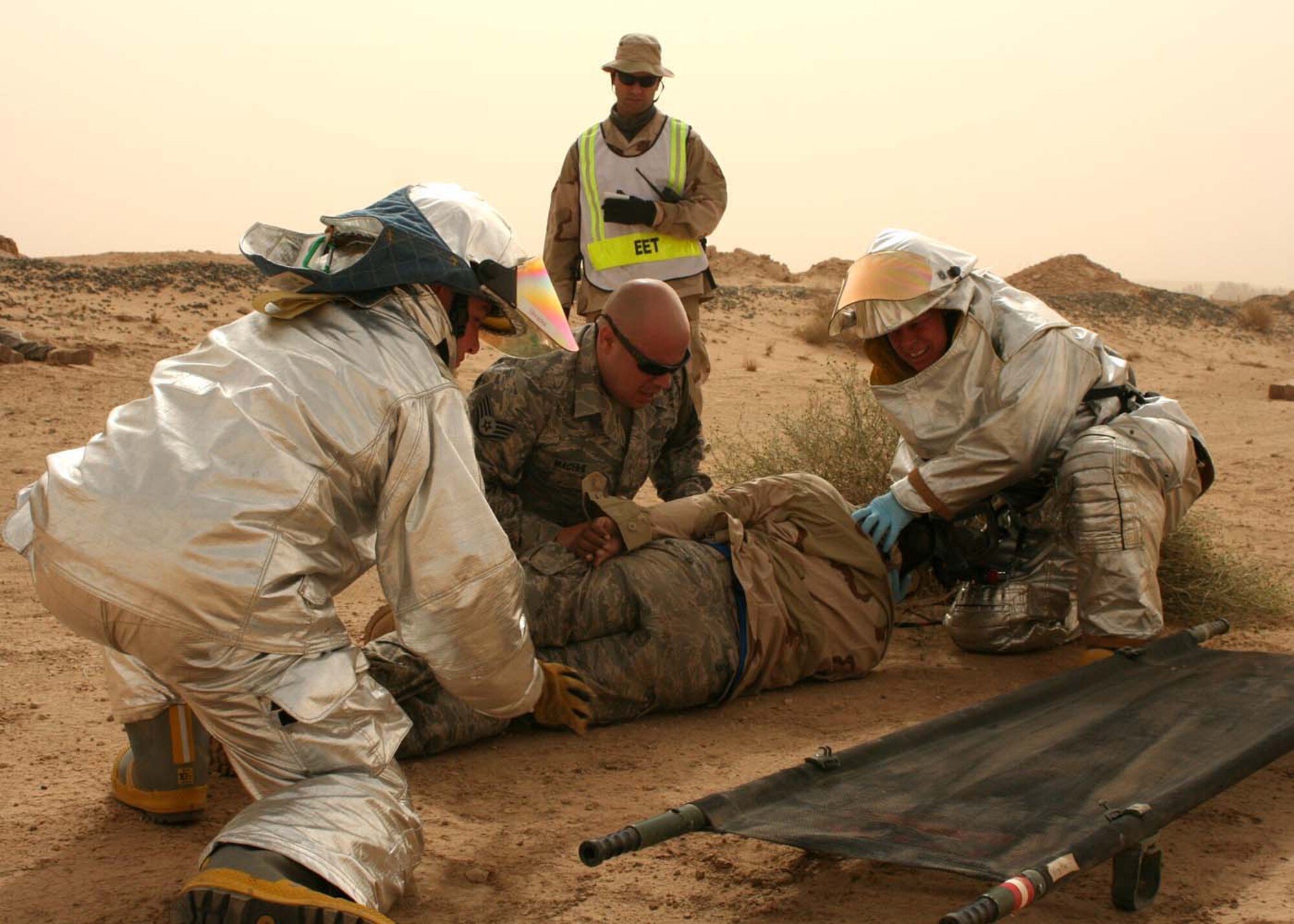 SOUTHWEST ASIA -- Members from the 386th Expeditionary Civil Engineering Squadron and the 386th Expeditionary Security Forces Squadron work together to move a mock victim onto a litter while being inspected during an exercise at an air base in Southwest Asia, Feb. 23. The exercise was an evaluation of multi-agency response to a mass casualty incident. (U.S. Air Force photo/ Staff Sgt. Shaun Denton)