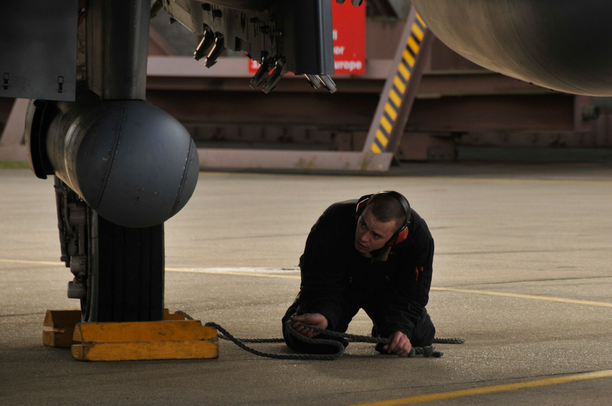 Airman 1st Class Dominic Dizes, 48th Aircraft Maintenance Squadron F-15 crew chief, prepares to un-chock the tires of an F-15 Strike Eagle Feb. 11, 2009, at RAF Lakenheath, England. Wheel chocks ensure the aircraft doesn't move while the crew chiefs perform a final pre-flight inspection. (U.S. Air Force photo by Airman 1st Class Perry Aston) 