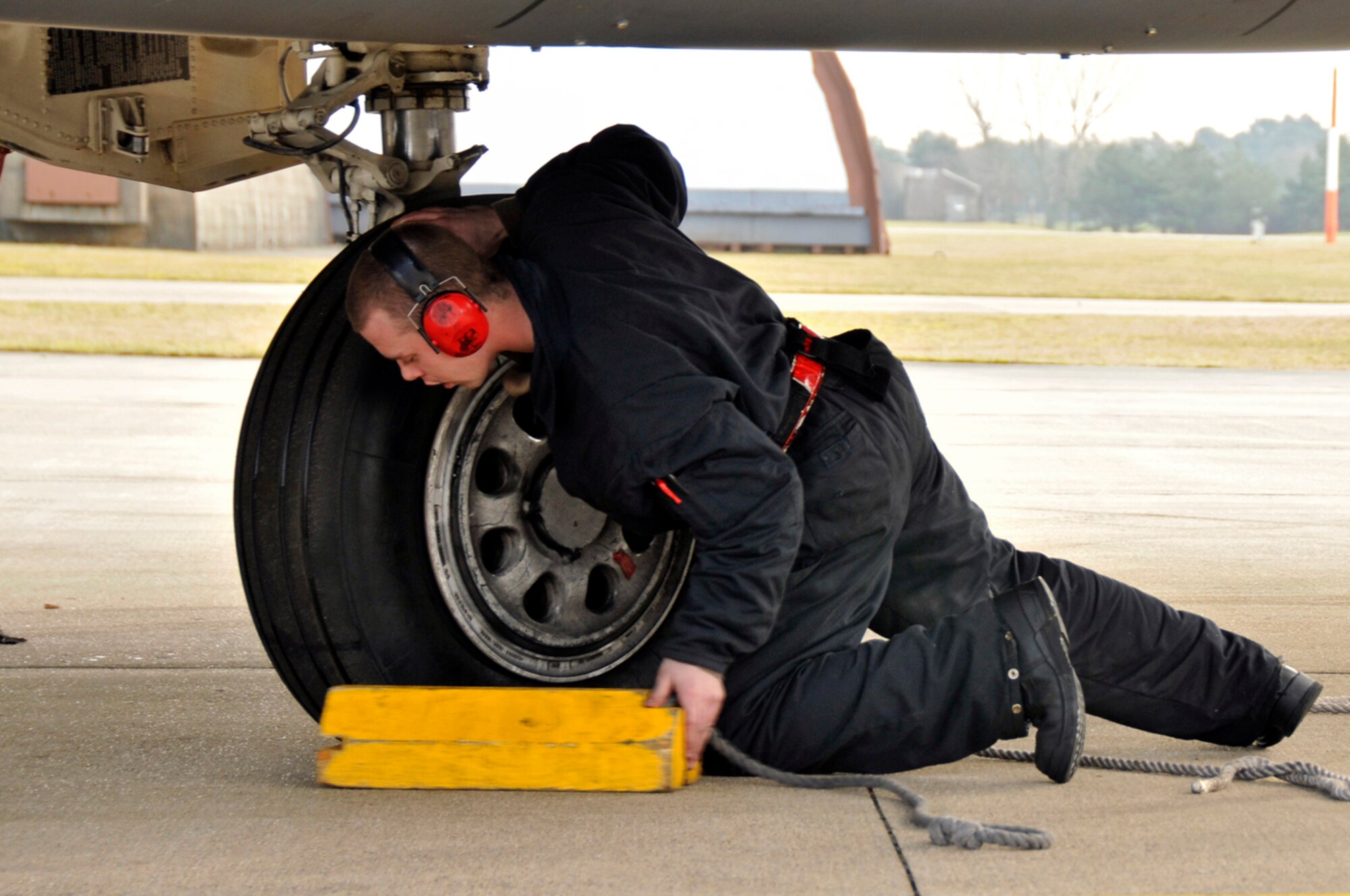 Airman 1st Class Dominic Dizes, 48th Aircraft Maintenance Squadron F-15 crew chief, throws a wheel chock underneath one of the wheels of a F-15 Strike Eagle Feb. 11, 2009, at RAF Lakenheath, England. Wheel chocks will ensure the aircraft doesn't move while the crew chiefs perform a final pre-flight inspection. (U.S. Air Force photo by Airman 1st Class Perry Aston) 