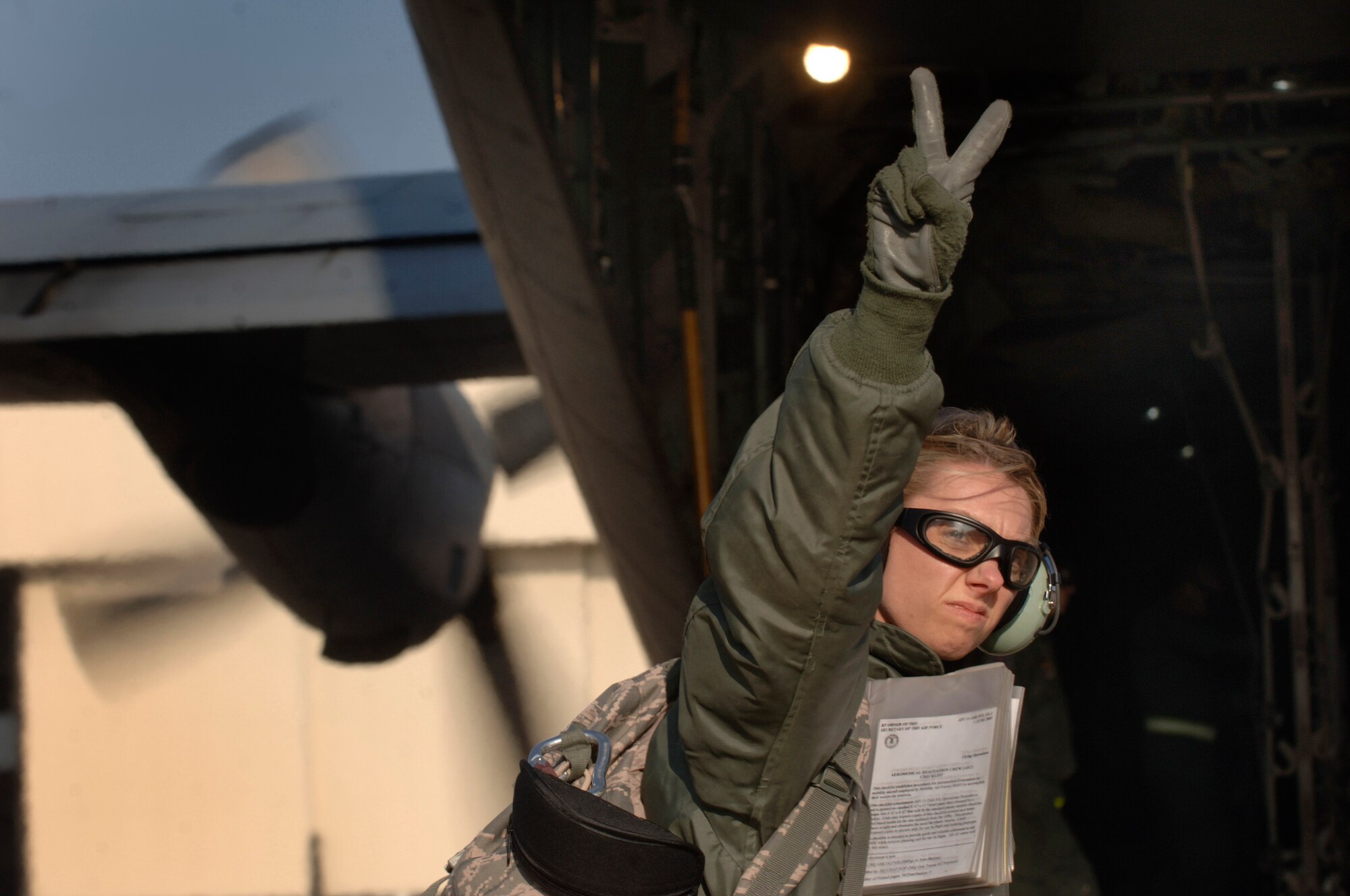Serving as a safety spotter for an engines-running-off load of medical equipment and personnel, Capt. Stephanie Ellenburg, flight nurse, signals the number of able bodies needed for the next off at Ramstein Air Base, following a three-hour aeromedical evacuation training sortie. The flight-qualified healthcare providers, assigned to the 86th Aeromedical Evacuation Squadron, fly weekly with the 37th and 38th Airlift Squadron's C-130 fleet  to remain proficient in their skills.  (Department of Defense photo by Master Sgt. Scott Wagers)