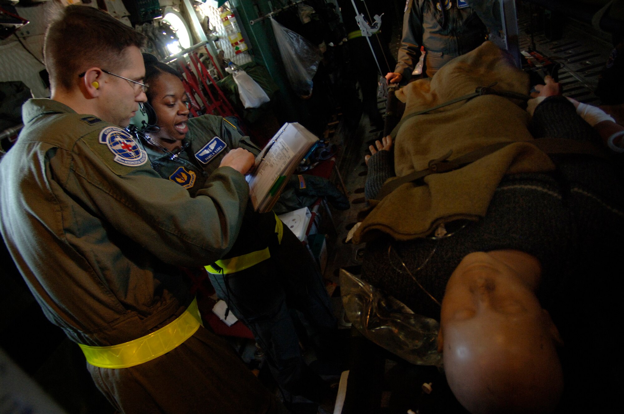 In preparation for an emergency landing training scenario aboard a C-130 Hercules flying over southern Germany, Capts. Troy Kinion and Pamela Banks, flight nurses, cover a checklist detailing how to properly secure patients and medical equipment for a potentially rough landing. The flight-qualified healthcare providers, assigned to the 86th Aeromedical Evacuation Squadron, fly weekly with Ramstein's 37th and 38th Airlift Squadron's C-130 fleet to remain proficient in their skills.  (Department of Defense photo by Master Sgt. Scott Wagers) 