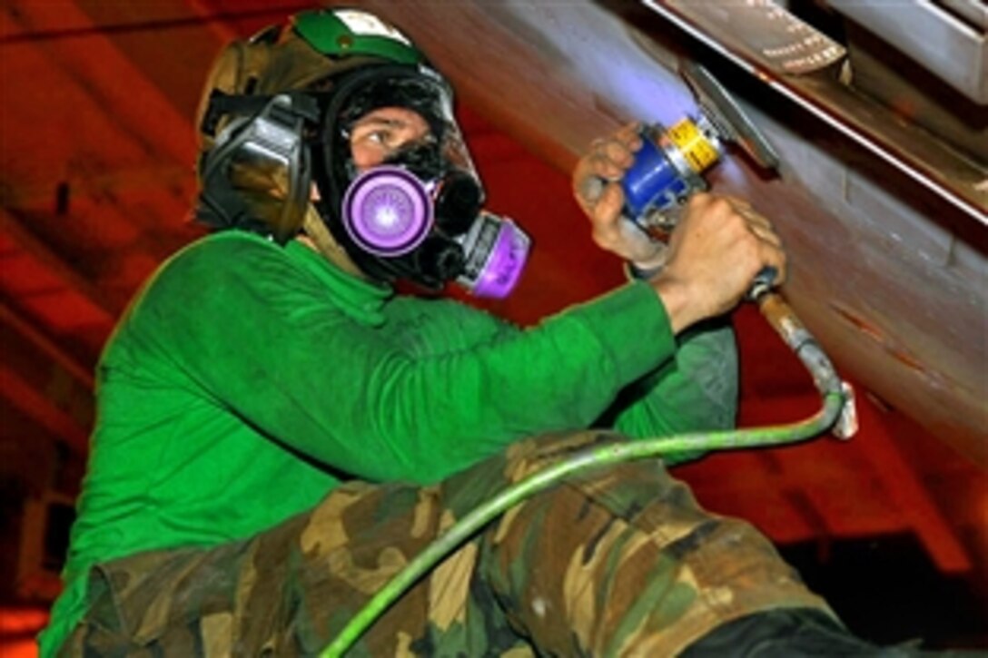 U.S. Navy Petty Officer 3rd Class Bradley Wroblos sands corrosion from the wing of an EA-6B Prowler in the hangar bay aboard the aircraft carrier USS John C. Stennis in the Pacific Ocean, Feb. 22, 2009.