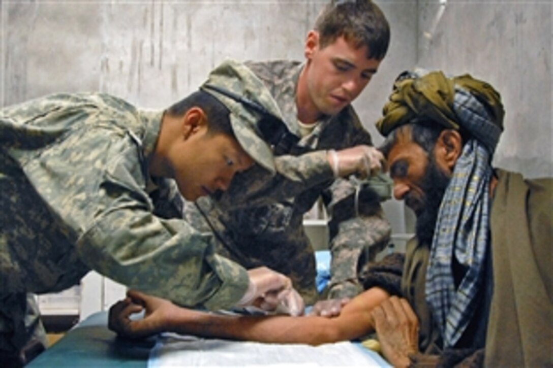 U.S. Army Pvt. Trung Nguyen, left, and Spc. Michael Vanalstyne administer care to a village elder at a medical clinic near Forward Operating Base Lane in Zabul province, Afghanistan, Feb. 25, 2009. Nguyen and Vanalstyne are assigned to Company B, 1st Battalion, 4th Infantry Regiment.