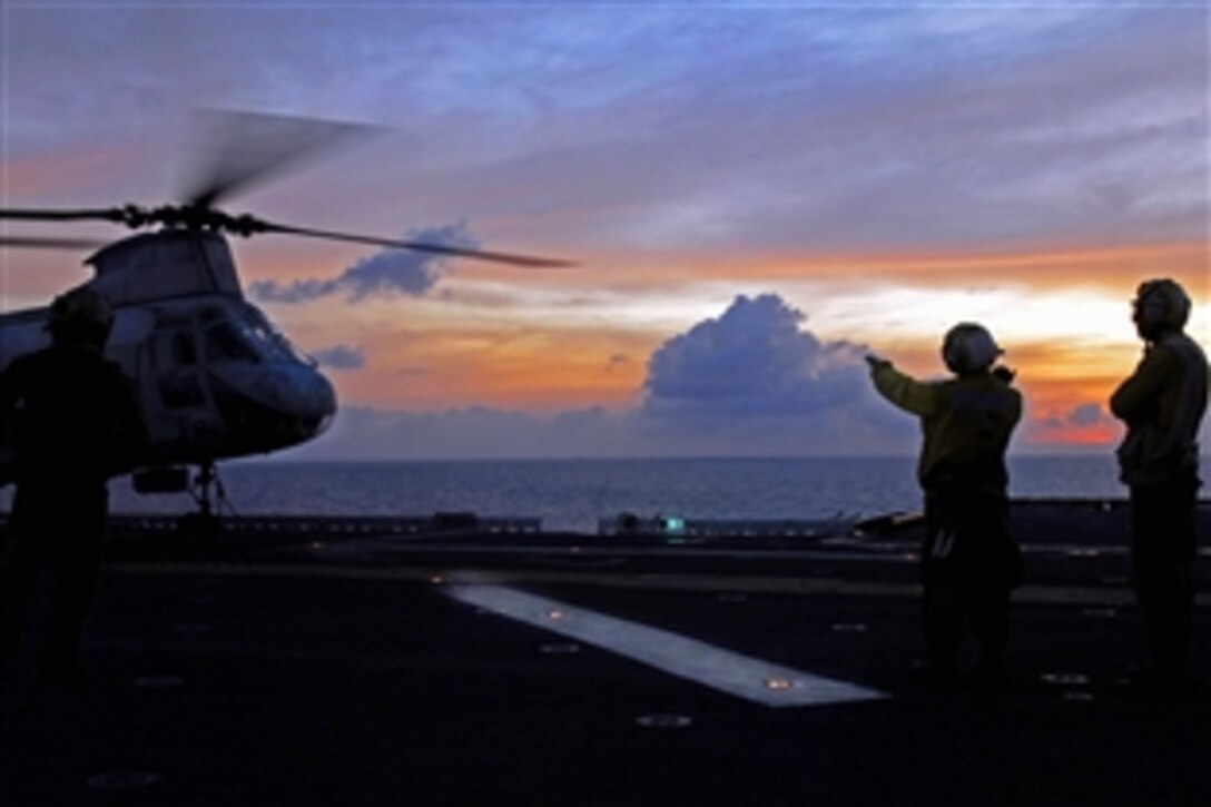 U.S. Navy Seaman David Neiman, left, and Petty Officer 3rd Class Apolinar Garcia prepare to move a CH-46E Sea Knight helicopter during evening flight operations aboard the forward-deployed amphibious assault ship USS Essex in the Gulf of Thailand, Feb. 25, 2009.