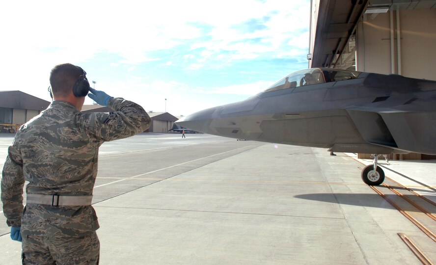 Airman 1st Class Joshua Zappa-Behrens, 7th Aircraft Maintenance Unit, salutes an F-22A pilot ready for final checks at the end of runway at Holloman Air Force Base, N.M., Feb. 26. Airman Zappa-Behrens and members of Team Holloman took part in a mock deployment exercise to Anderson Air Base, Guam. (U.S. Air Force photo/Airman 1st Class Veronica Salgado)