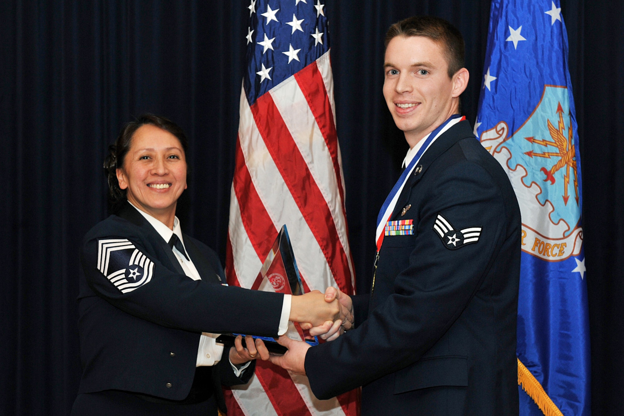OFFUTT AIR FORCE BASE, Neb. ?  Chief Master Sgt. Paula Lopez, Air Force Weather Agency chief of knowledge operations management, presents Senior Airman Scott William, 97th Intelligence Squadron, with a distinguished graduate award for the James M. McCoy Airman Leadership School here Feb. 12. Through four weeks of dedication and hard work, 37 graduates have enhanced leadership skills to guide this next generation of airman coming into the Air Force.