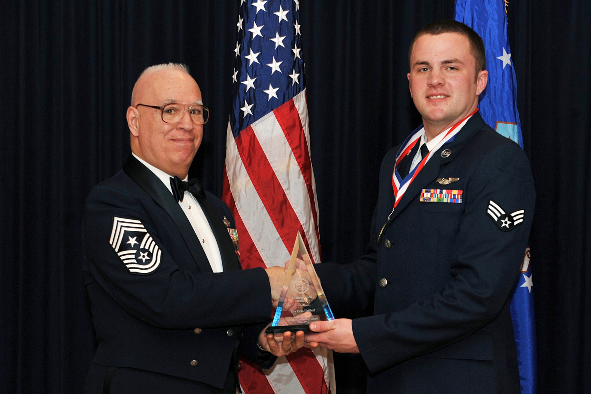 OFFUTT AIR FORCE BASE, Neb. ?  Retired Chief Master Sgt. Michael Parente  presents Senior Airman Evan Hatfield, 97th Intelligence Squadron, with a distinguished graduate award for the James M. McCoy Airman Leadership School class 09-C here Feb 12. Through four weeks of dedication and hard work, 37 graduates have enhanced leadership skills to guide this next generation of airman coming into the Air Force.