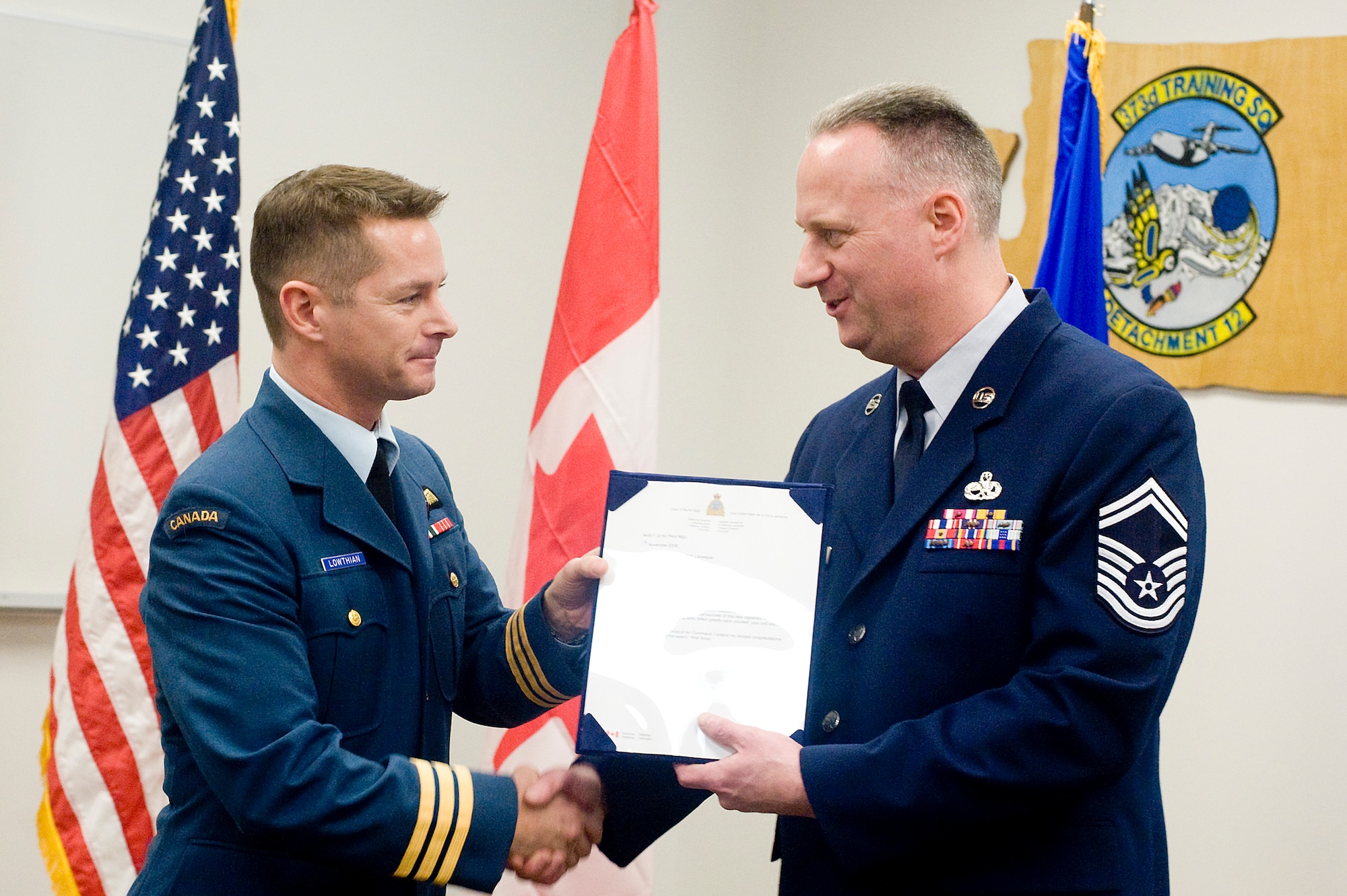 Canadian air force Lt. Col. David Lowthian, 429th Transport Squadron commander, presents Senior Master Sgt. Douglas Levesque, 373rd Training Squadron, Det. 12 chief, the Canadian Forces Air Command Commendation during a ceremony Feb. 24 at the squadron’s headquarters. (U.S. Air Force photo/Abner Guzman)