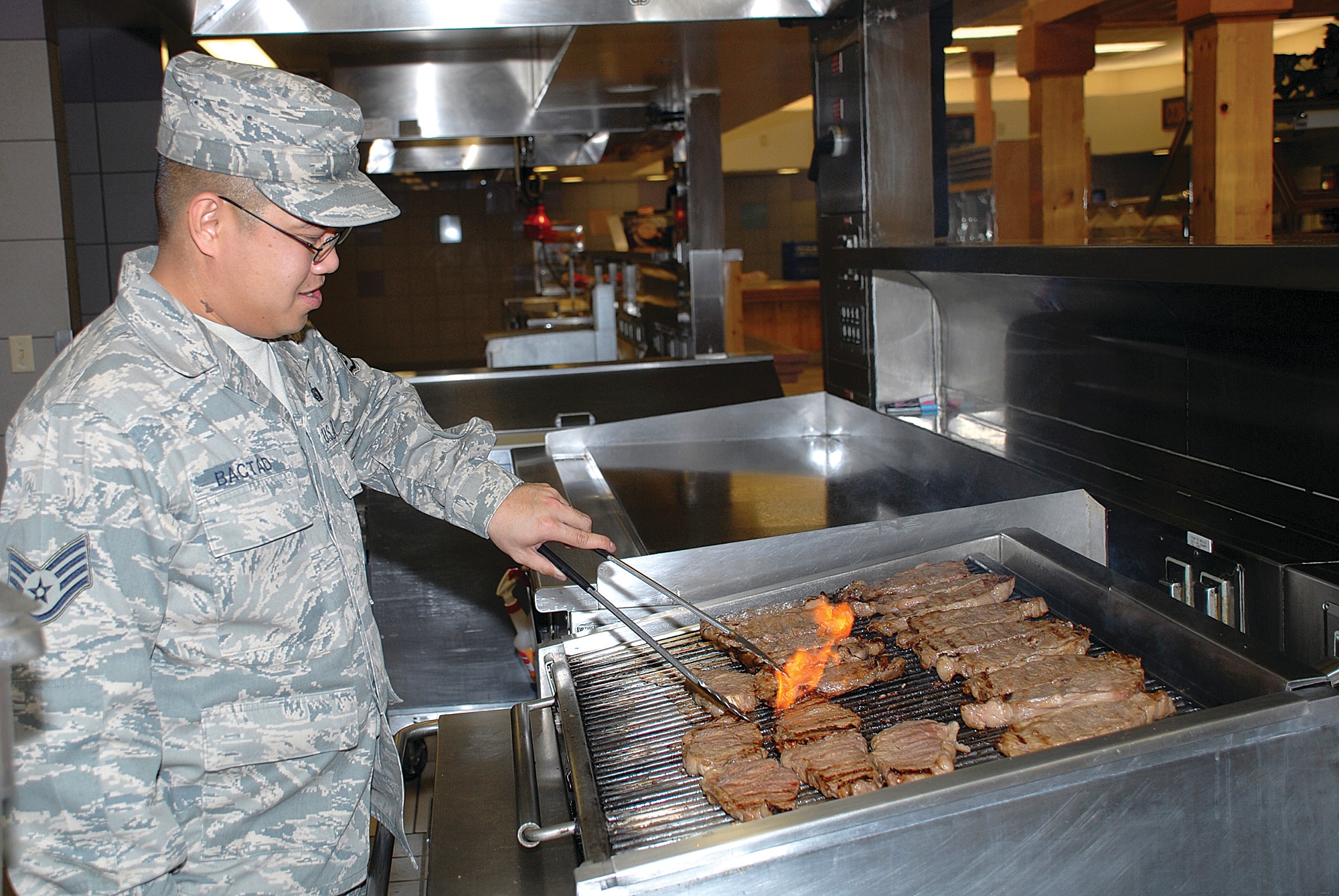Staff Sgt. Christopher Bactad, 56th Services Squadron Food Service specialist, flips over steaks on the grill in the Ray V. Hensman Dining Facility Monday. (U.S. Air Force photo/ Airman 1st Class Traci Forte)