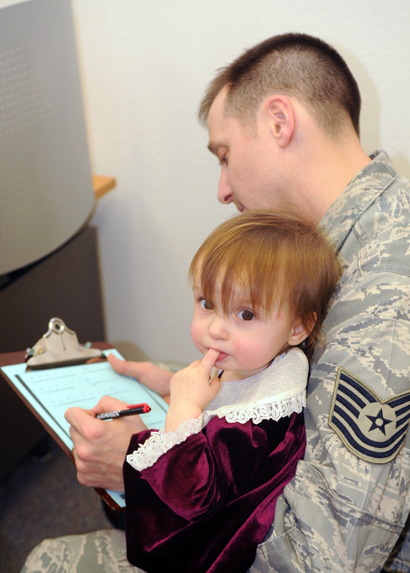 SPANGDAHLEM AIR BASE, Germany – Tech. Sgt. Eugene Taylor, U.S. Air Forces in Europe American Forces Network Detachment 9, holds his daughter, Joy, as he signs up for the Mosel Reintegration Retreat, Feb. 24. The Mosel Reintegration Retreat is a weekend getaway for military couples, offered by the Airman & Family Readiness Center. (U.S. Air Force photo by Airman 1st Class Staci Miller)