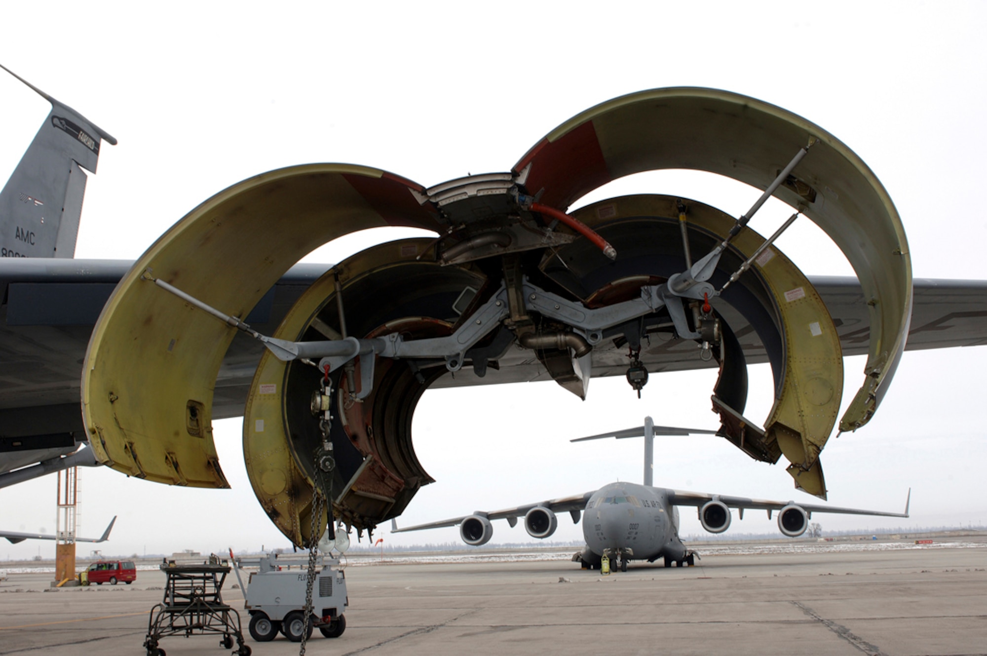 A KC-135 Stratotanker wing engine strut housing patiently awaits a new turbofan engine. Maintainers from the 376th Expeditionary Aircraft Maintenance Squadron determined that critical components of the interior of the previous engine were severely degraded and worn out and that an engine change was necessary. Behind the KC-135 sits a C-17 Globemaster III, which will soon carry another load of personnel and cargo into Afghanistan. (U.S. Air Force photo/Tech. Sgt. Elizabeth Weinberg)