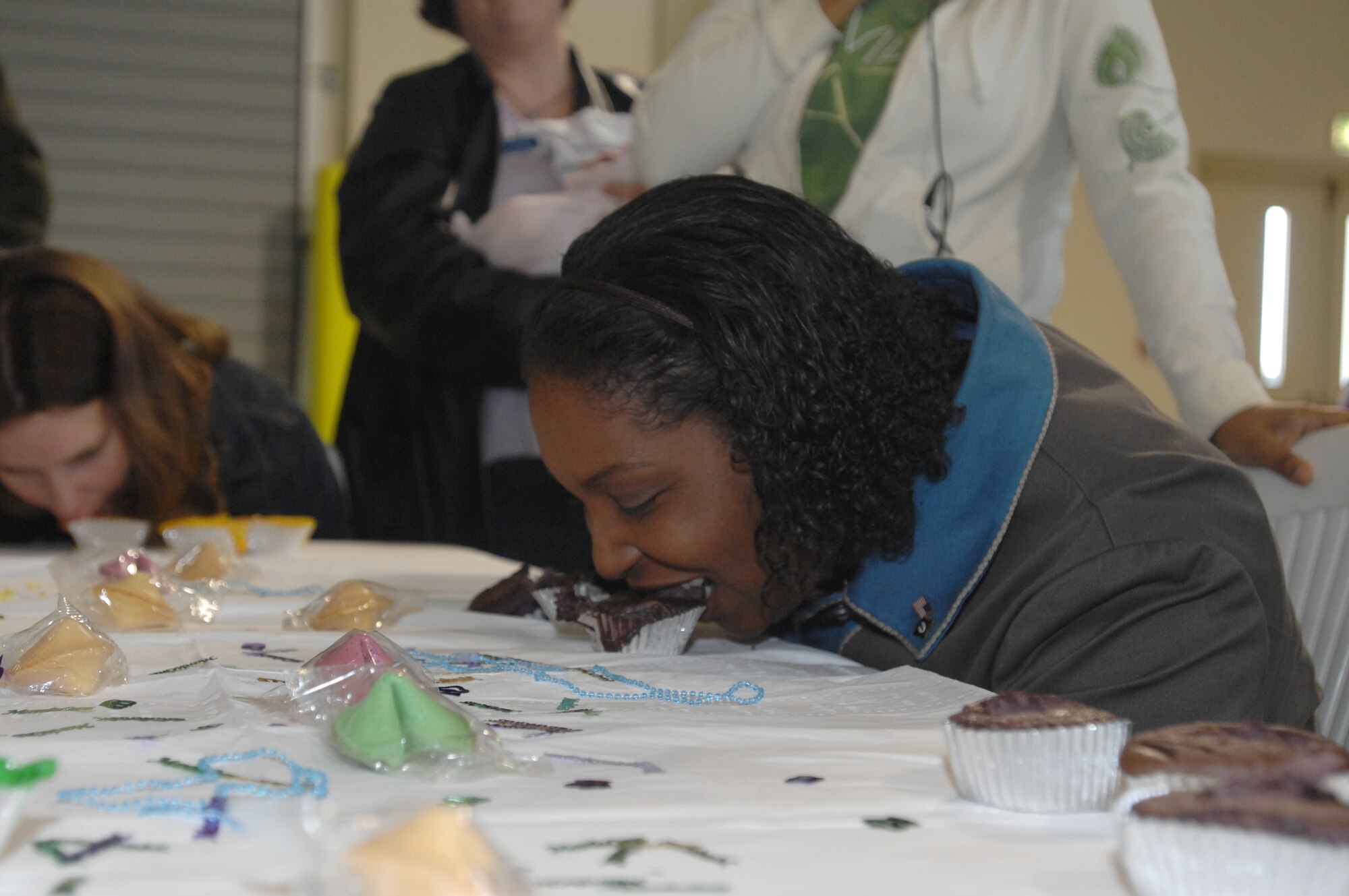 Annemarie Benson participates in a cupcake surprise contest Feb. 18 during the Spouse It Up event at the Personnel Alert Holding Area.  During the contest, spouses had to dig through four colored cupcakes without using their hands in order to find prize winning trinkets. (U.S. Air Force photo/Airman 1st Class Tabitha Mans)          