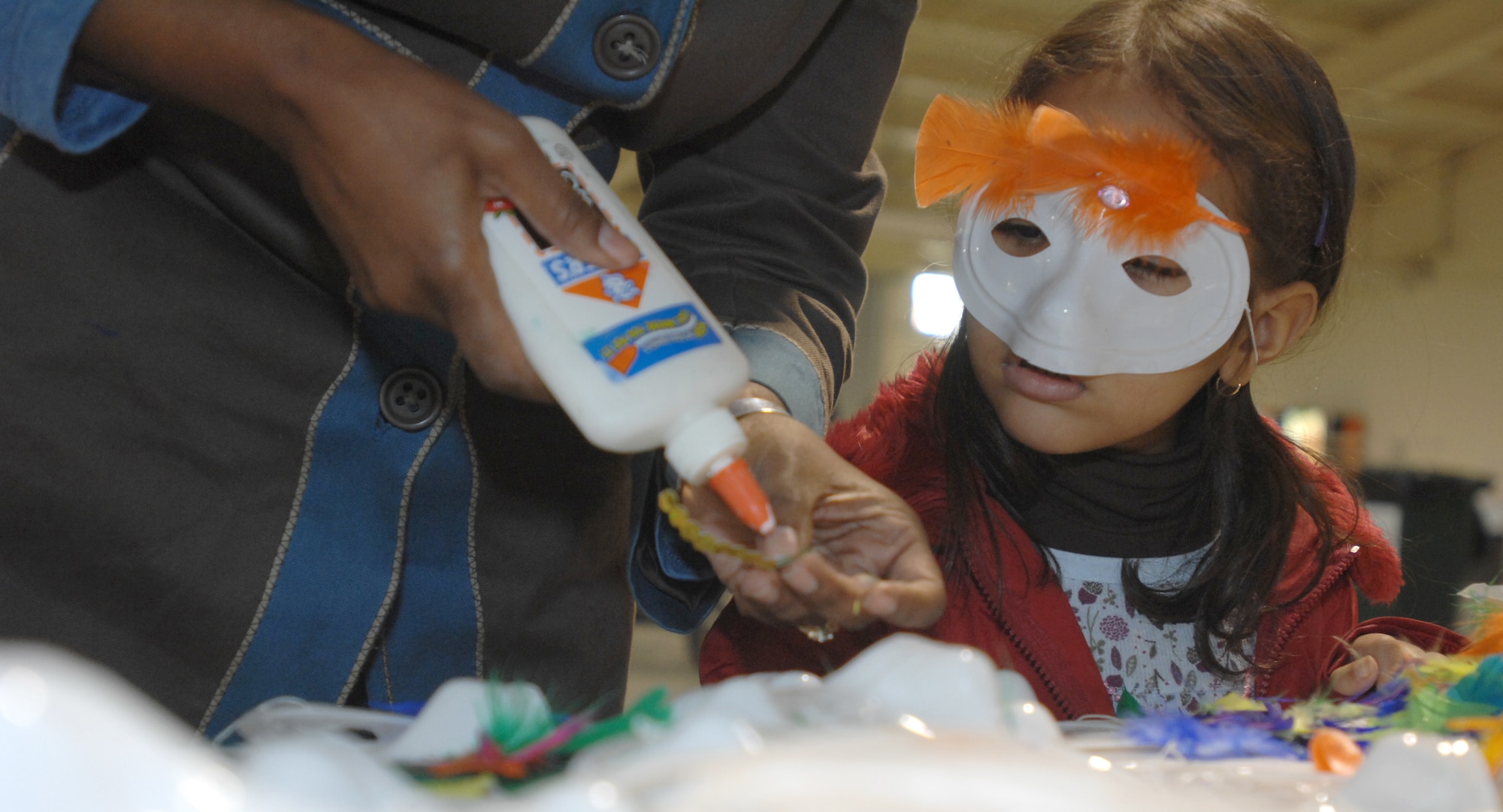 Samantha Benson decorates a Mardi Gras mask with the help of her mother Annemarie Benson during Spouse It Up Feb. 18 at the Personnel Alert Holding Area. This month's event was hosted by the Aviano Officers and Civilian Spouses Club and the Aviano Community and Enlisted Spouses group.  (U.S. Air Force photo/Airman 1st Class Tabitha Mans)