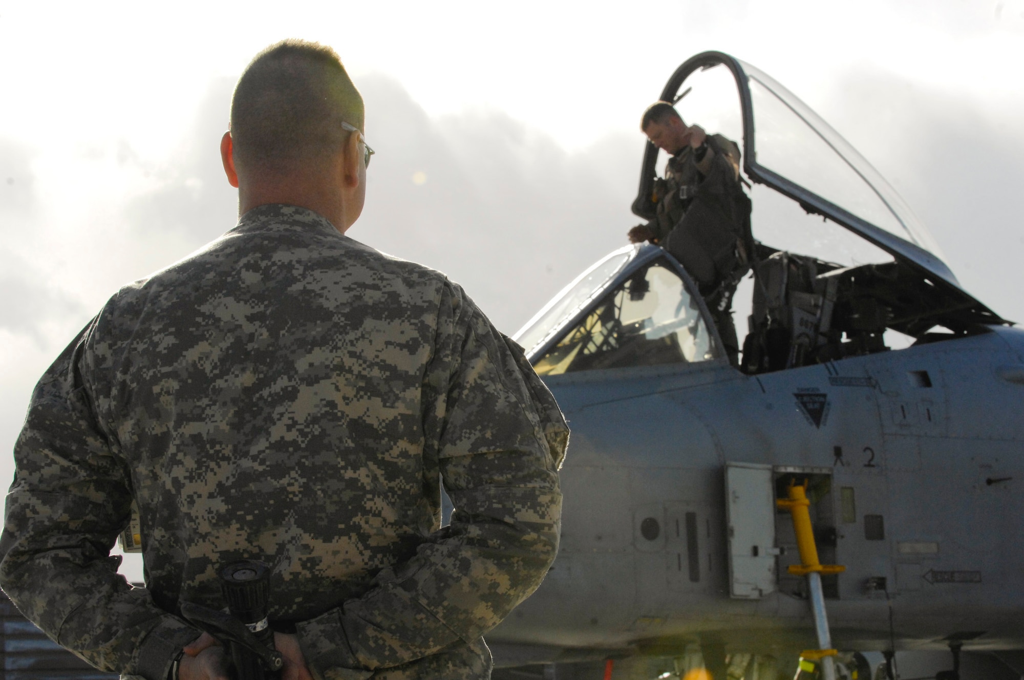 (Left) Army Lt. Col. George Chizmar, Air Force ground liason officer, hides a fire hose behind his back as Lt. Col. Sam "Spam" Milam, 75th Expeditionary Fighter Squadron commander, prepares to dismount his A-10C Thunderbolt II after logging his unit's 10,000th combat flight hour with one Air Expeditionary Force rotation. The lieutenant colonel was congratulated shortly thereafter with a short burst of water from the base fire department. This was the first time a squadron deployed here reached 10,000 combat hours. The 75th EFS arrived here in September for a four-month deployment, but was extended to six months. The A-10 Thunderbolt II was the first tactical fighter aircraft to deploy here in 2002.  