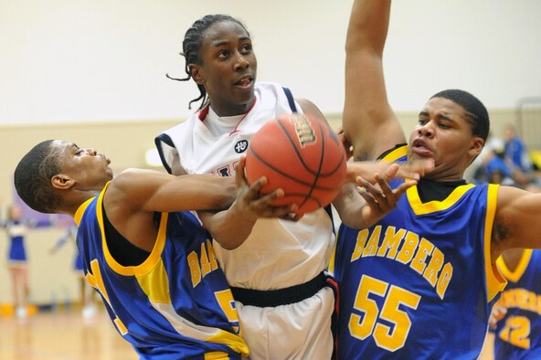 Aviano's Jamal Tuck draws a fouls as he drives between Bamberg's Joshua Robinson, left, and Cortez Lindsey. Aviano beat the Barons 85-59 to win the Division II championship at the DODDS-Europe basketball finals in Mannheim, Germany, Saturday night. (Photo by Michael Abrams. Used with permission from Stars and Stripes. ? 2009 Stars and Stripes)