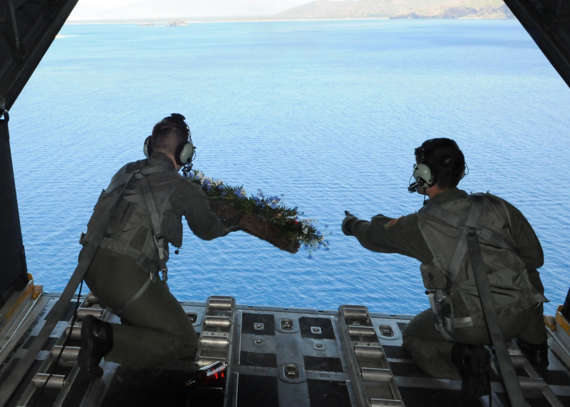 NEAR CAPONES ISLAND, Philippines -- Staff Sgts. Nicholas Adams (left) and Steve Pressler, 1st Special Operations Squadron loadmasters, release a memorial wreath out the back of a MC-130H Combat Talon II Feb. 26 to honor fallen brethren that were lost 28 years ago when a 1st SOS MC-130E, call sign STRAY59, crashed during an exercise killing eight crew members and 15 passengers. The crew of GOOSE99 flew from Kadena Air Base to reach the exact coordinates of the crash site to release the ceremonial wreath. The memorial flight has been flown every year since the tragic accident in 1981. (U.S. Air Force photo by Tech. Sgt. Aaron Cram)
