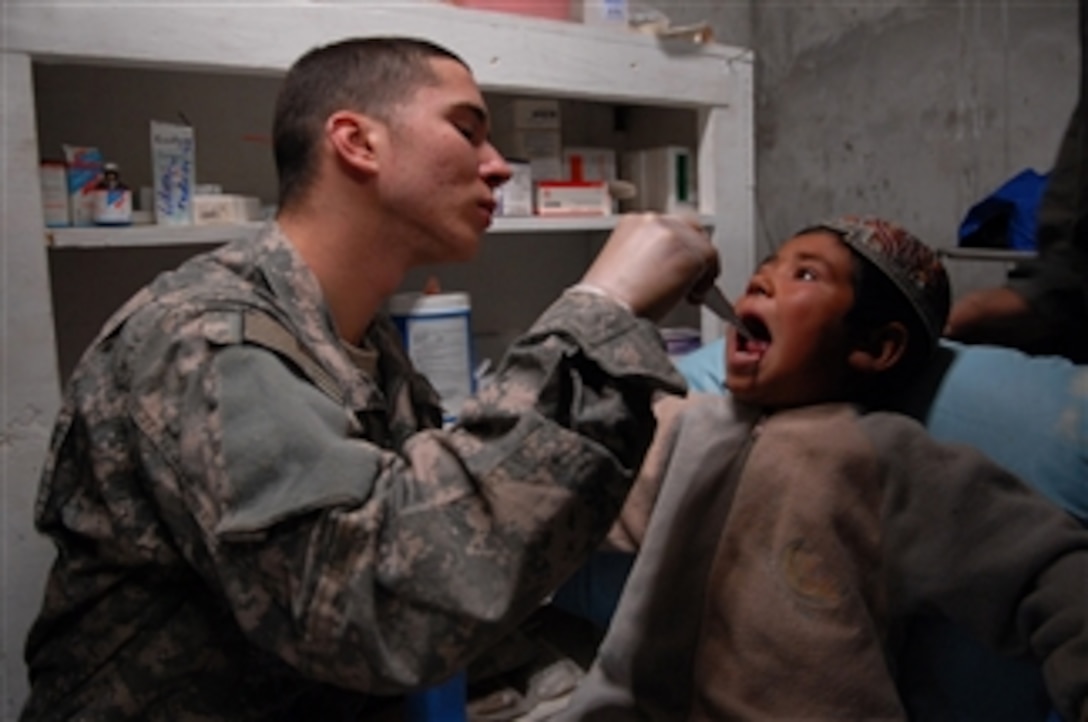 U.S. Army Pfc. Ryan Coelho, a medic with Bravo Company, 1st Battalion, 4th Infantry Regiment, treats a boy who needs a tooth extraction at a medical clinic near Forward Operating Base Lane in the Zabul province of Afghanistan on Feb. 25, 2009.  