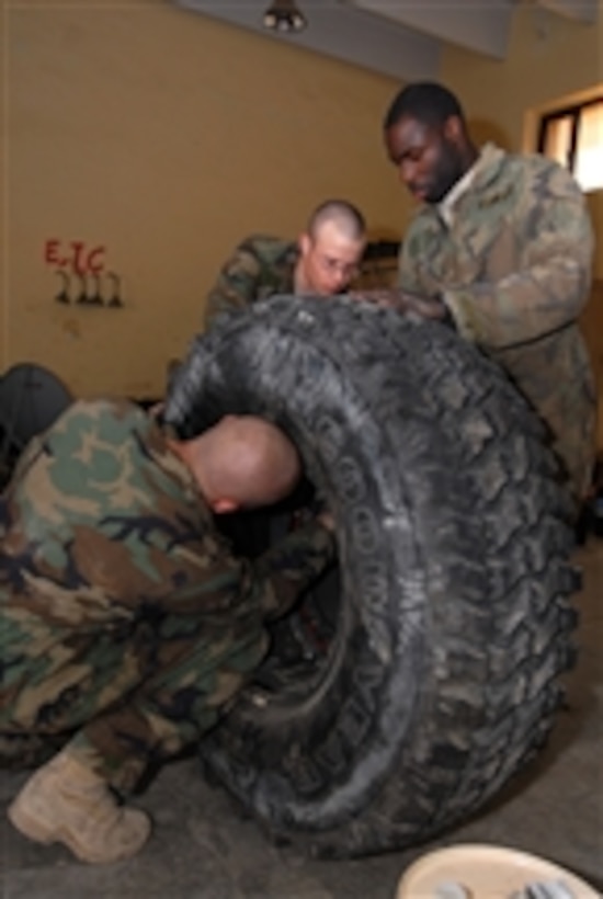 U.S. Army Sgt. Raymond Averesch (left), Pfc. Curtis Lacher (center) and Spc. Cedrick Griffin, with the Military Transition and Training Team, assemble a wheel for a mine-resistant, ambush-protected vehicle in Kadhimiya, Iraq, on Feb. 23, 2009.  