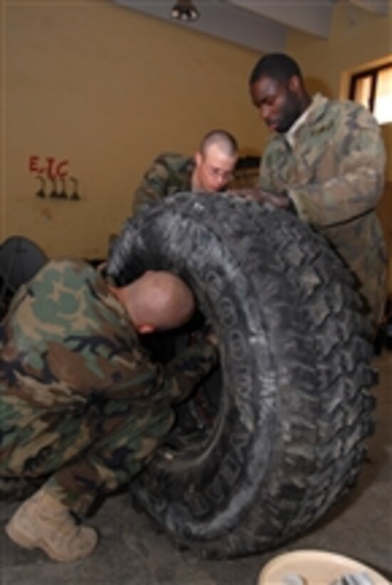 U.S. Army Sgt. Raymond Averesch (left), Pfc. Curtis Lacher (center) and Spc. Cedrick Griffin, with the Military Transition and Training Team, assemble a wheel for a mine-resistant, ambush-protected vehicle in Kadhimiya, Iraq, on Feb. 23, 2009.  