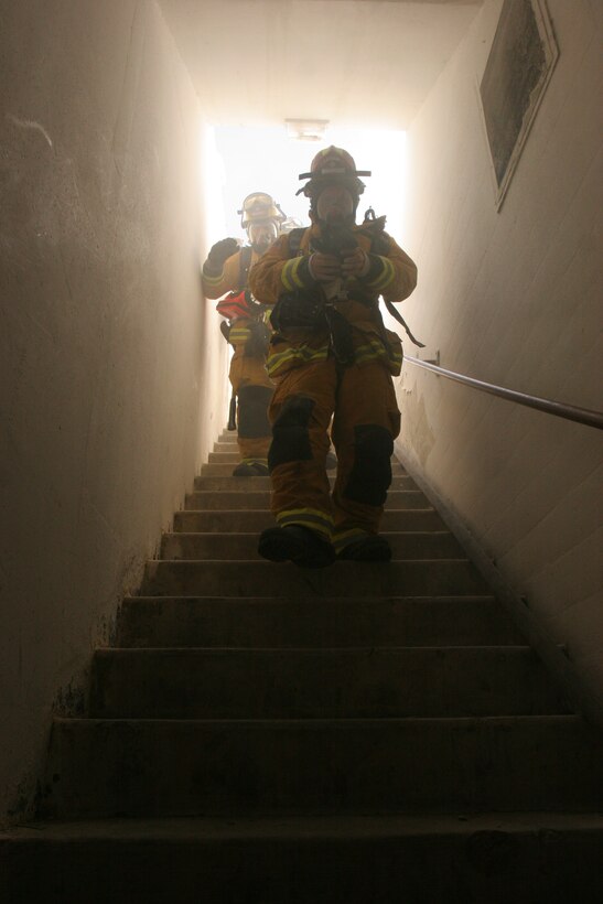 Firefighters with North County’s Fire Protection District rush down the stairs to save fallen fellow firefighters during Rapid Intervention Crew training at Naval Weapons Station Seal Beach, Detachment Fallbrook.