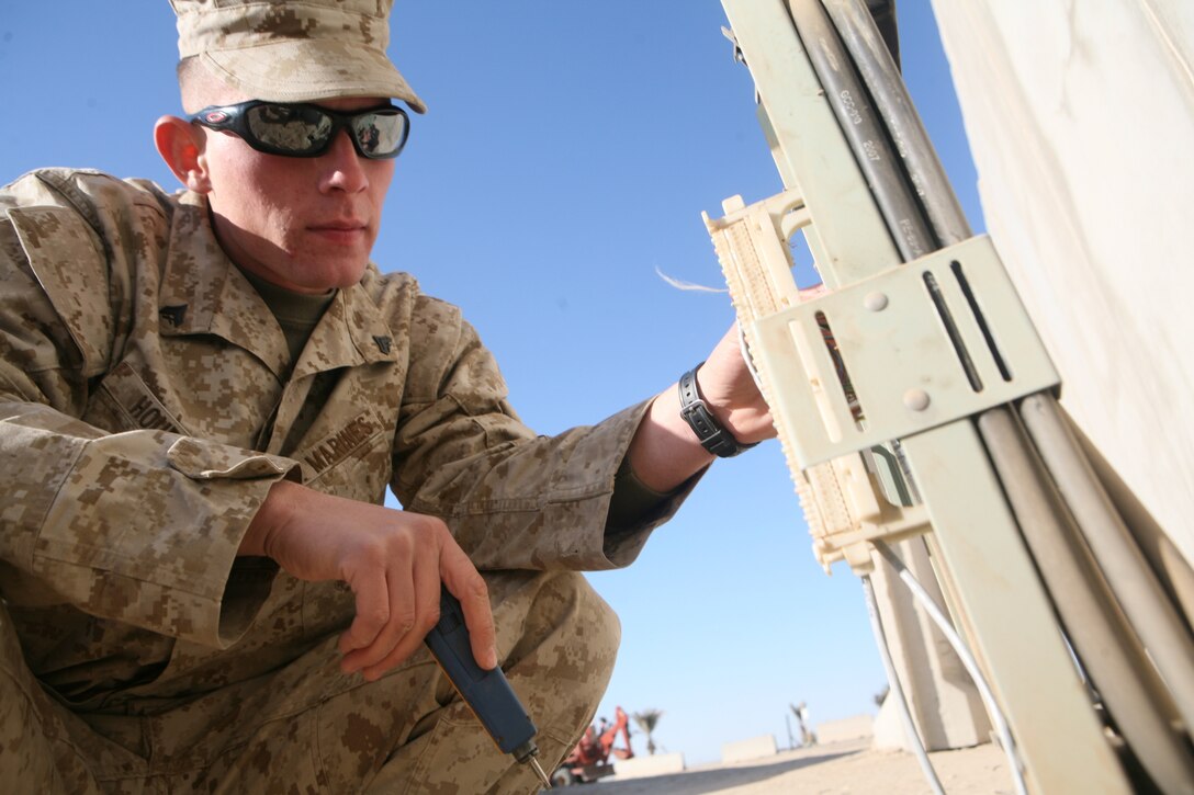 Cpl. Alex J. Joursey, a construction wireman with 9th Communications Battalion, attached to the Camp Baharia Technical Control Facility, prepares a pedestal for new telephone service at Camp Baharia, Iraq, Jan. 1. Field wiremen set up a commercialized telephone system on the camp that improved Defense Switched Network capabilities.