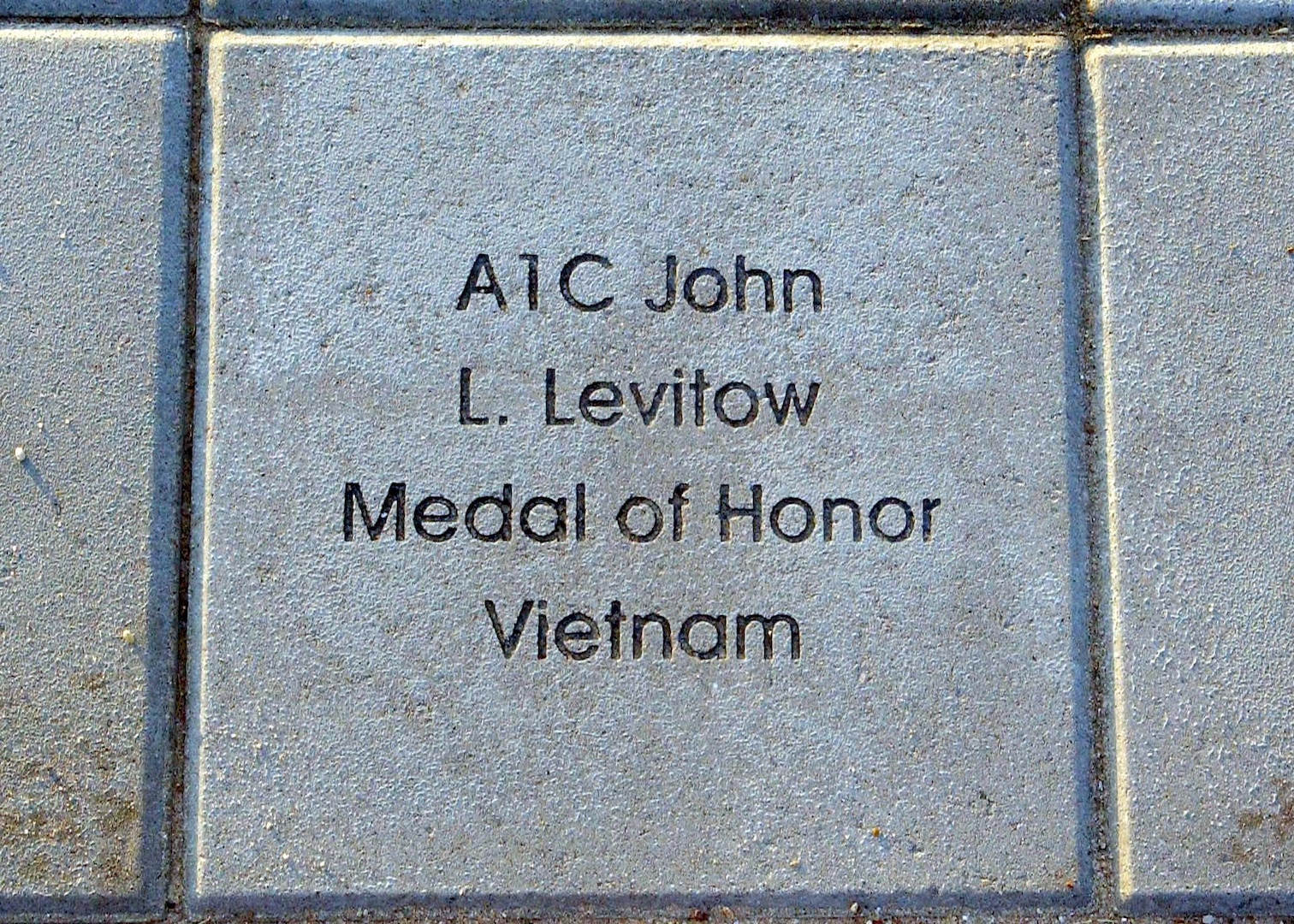 A stone bearing the etched name of Airman 1st Class John Levitow rests as one of the 1,024 paving the new Enlisted Heroes Walk at Lackland Air Force Base, Texas,   In all, 164 of the stones are etched with the names of enlisted servicemembers honored for their service during conflict. Airman Levitow, an AC-47 gunship loadmaster, became the lowest-ranking Airman ever to receive the Medal of Honor for exceptional heroism during the Vietnam War. (U.S. Air Force photo/Alan Boedeker)