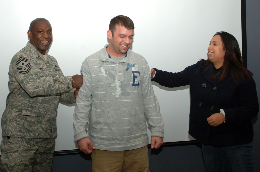 (Center) Staff Sgt. John Hertel, 28th Maintenance Operations Squadron information management manager, is promoted to the rank of technical sergeant through the Stripes for Exceptional Performers program, Jan. 2. Chief Master Sgt. Clifton Cole, 28th Bomb Wing command chief, and Sergeant Hertel’s wife, Susannah, tacked on Sergeant Hertel’s new stripes. (U.S. Air Force photo/Senior Airman Kasey Zickmund)