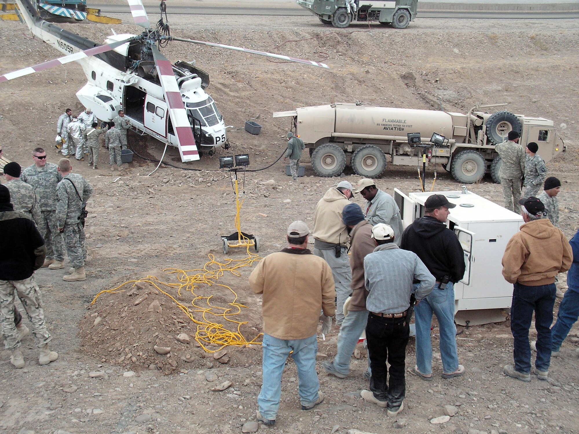 Emergency response workers and forward operating base personnel prepare a helicopter for removal after it crashed in a ditch Dec. 15, 2008, at an undisclosed location in Southwest Asia. Firefighters forward deployed from the 379th Expeditionary Civil Engineer Squadron were the first on scene.  (Courtesy photo)