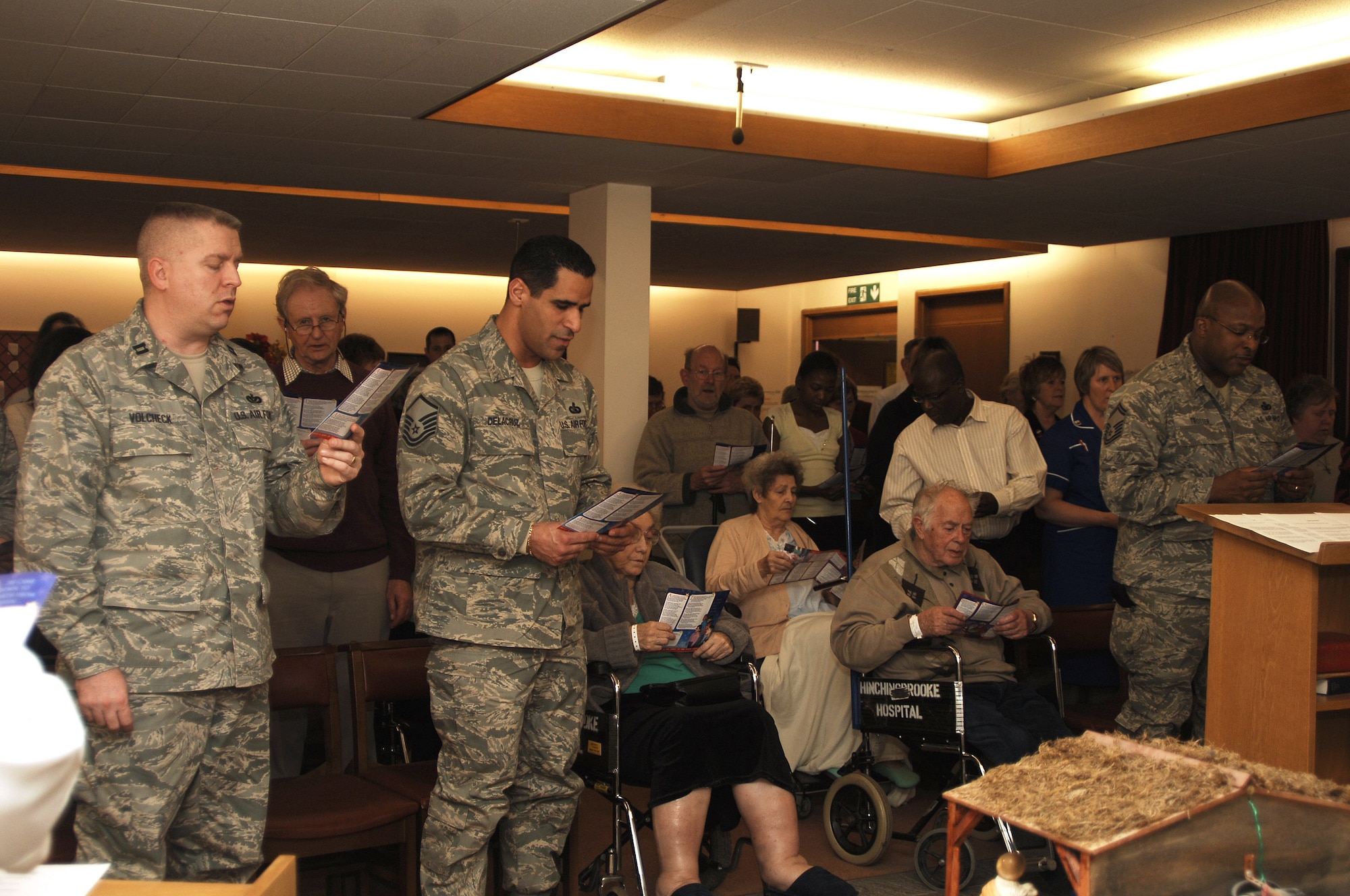 Airman from RAF Alconbury Air Force Base, United Kingdom, participates in a Christmas service at the Hitchingbrook Hosital, Huntingdon, United Kingdom, after escorting patients from various wards in the hospital. 