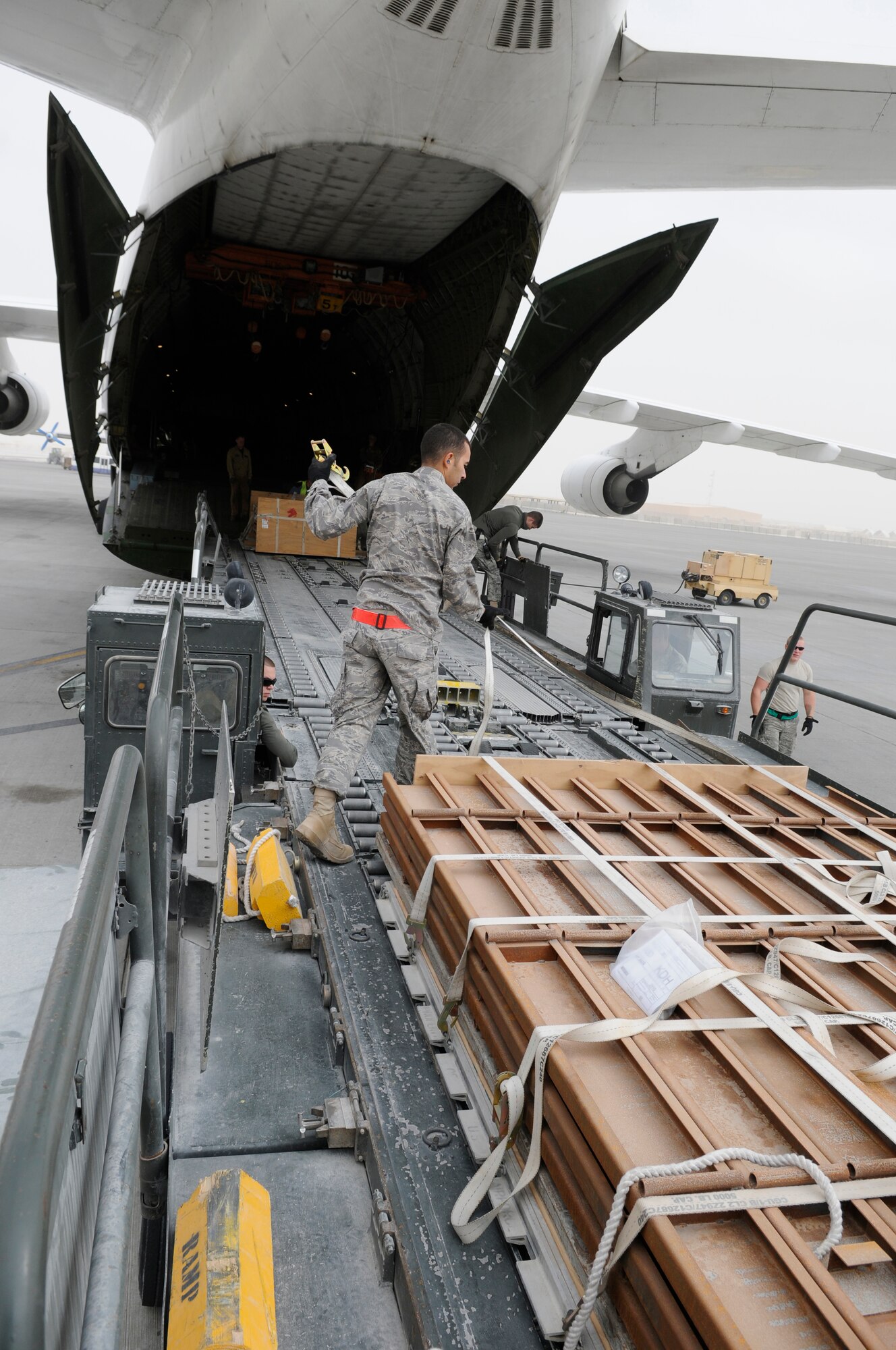 Airman 1st Class Fernando De Souza, an air transportation Journeyman assigned to the 8th Expeditionary Air Mobility Squadron, unlocks pallets on a 60K loader, Jan. 2, 2009, at an undisclosed air base in Southwest Asia.  The pallets are on two bridged 60K loaders and have to be unlocked for movement to a Russian Antonov 124-100 aircraft.  The Antonov will deliver a load of 7 pallets and a heavy equipment vehicle farther into the Central Command area of responsibility.  The equipment and supplies will support operations in Afghanistan.  Airman De Souza is a native of Sao Paulo, Brazil, and deployed from McGuire Air Force Base, N.J., in support of Operations Iraqi and Enduring Freedom and Joint Task Force-Horn of Africa.  (U.S. Air Force photo by Tech. Sgt. Michael Boquette/Released)