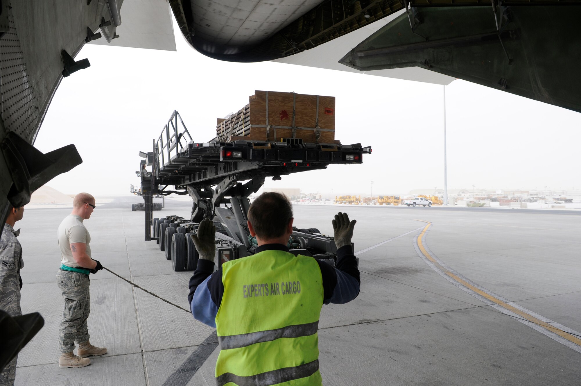 A crew member of the Russian Antonov 124-100 heavy lift cargo aircraft guides an 8th Expeditionary Air Mobility Squadron 60K loader into position, Jan. 2, 2009, at an undisclosed air base in Southwest Asia.  Two loaders are bridged for pushing pallets into the Antonov.  The Antonov is delivering a load of 7 pallets and a heavy equipment vehicle farther into the Central Command area of responsibility.  The equipment and supplies will support operations in Afghanistan.  (U.S. Air Force photo by Tech. Sgt. Michael Boquette/Released)