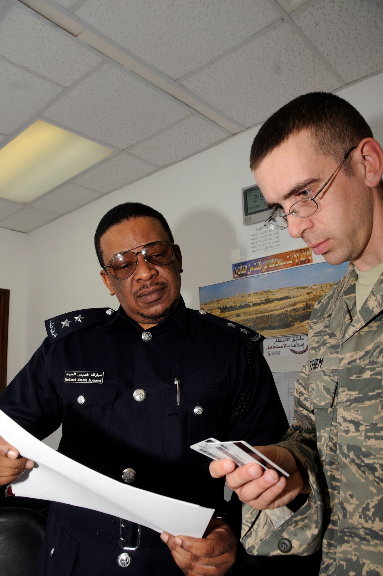 Staff Sgt. Norman Thiem checks indentification cards against information on an in processing worksheet with local national immigration personnel Dec. 30, 2008, at an air base in Southwest Asia. The immigration liaison is responsible for ensuring all members can deploy into and out of deployed locations and that all personnel respect the host nation's laws. Sergeant Thiem is a 379th Air Expeditionary Wing immigration liaison. He is a native of Tuscumbia, Ala., and deployed from Travis Air Force Base, Calif. (U.S. Air Force photo/Staff Sgt. Darnell T. Cannady) 
